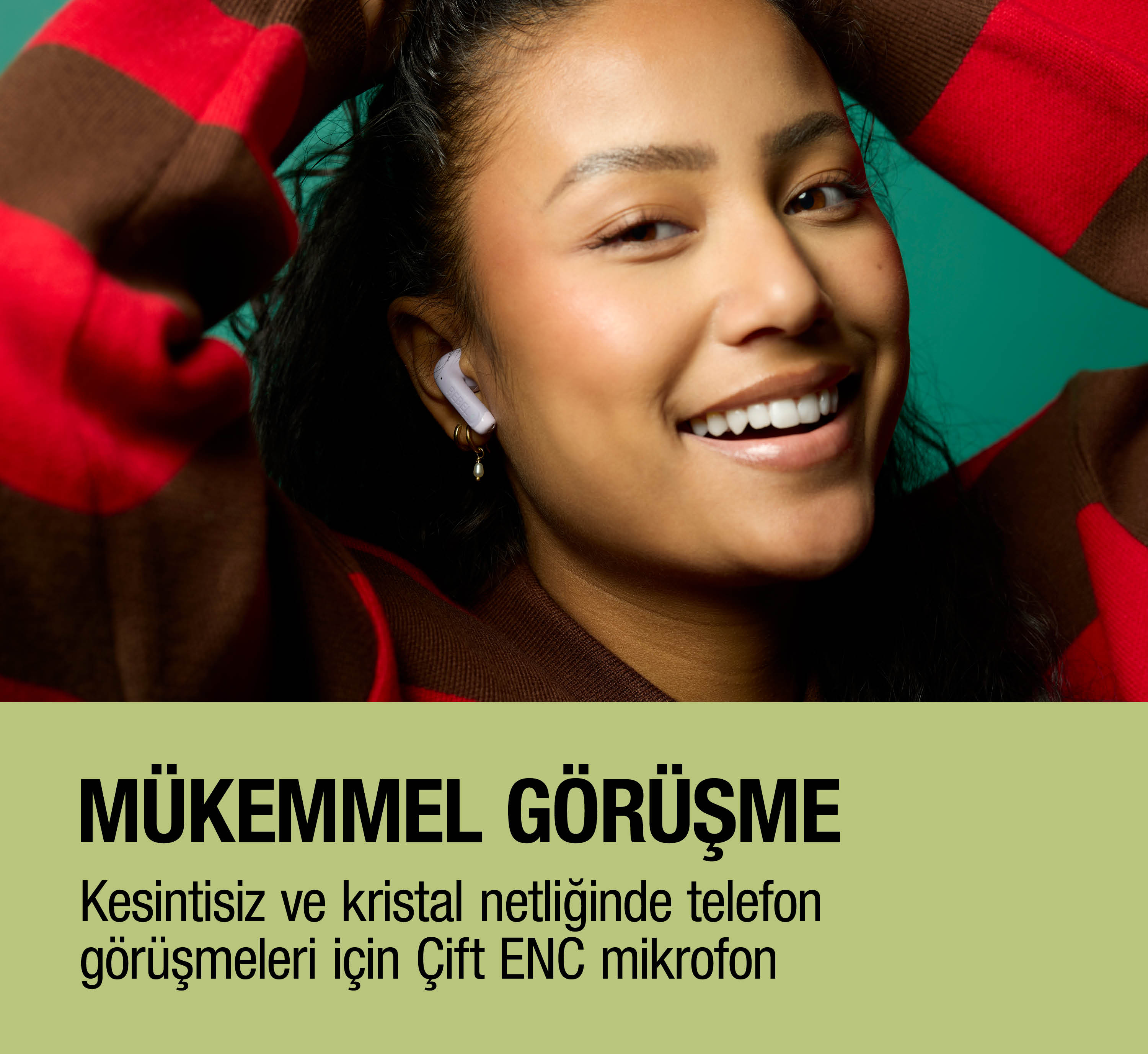 Beyaz kulaklıkla bir kadın gülümsüyor, kırmızı ve kahverengi çizgili süveter giyiyor.