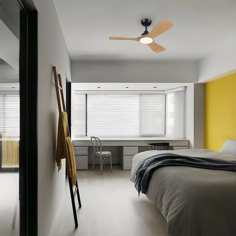 Ventilador de techo de madera con luz sobre una cama y un escritorio.