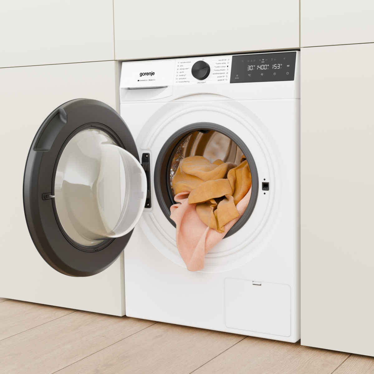 Fehér Gorenje mosógép nyitott ajtóval, ruhákkal bent. Digitális kijelző.