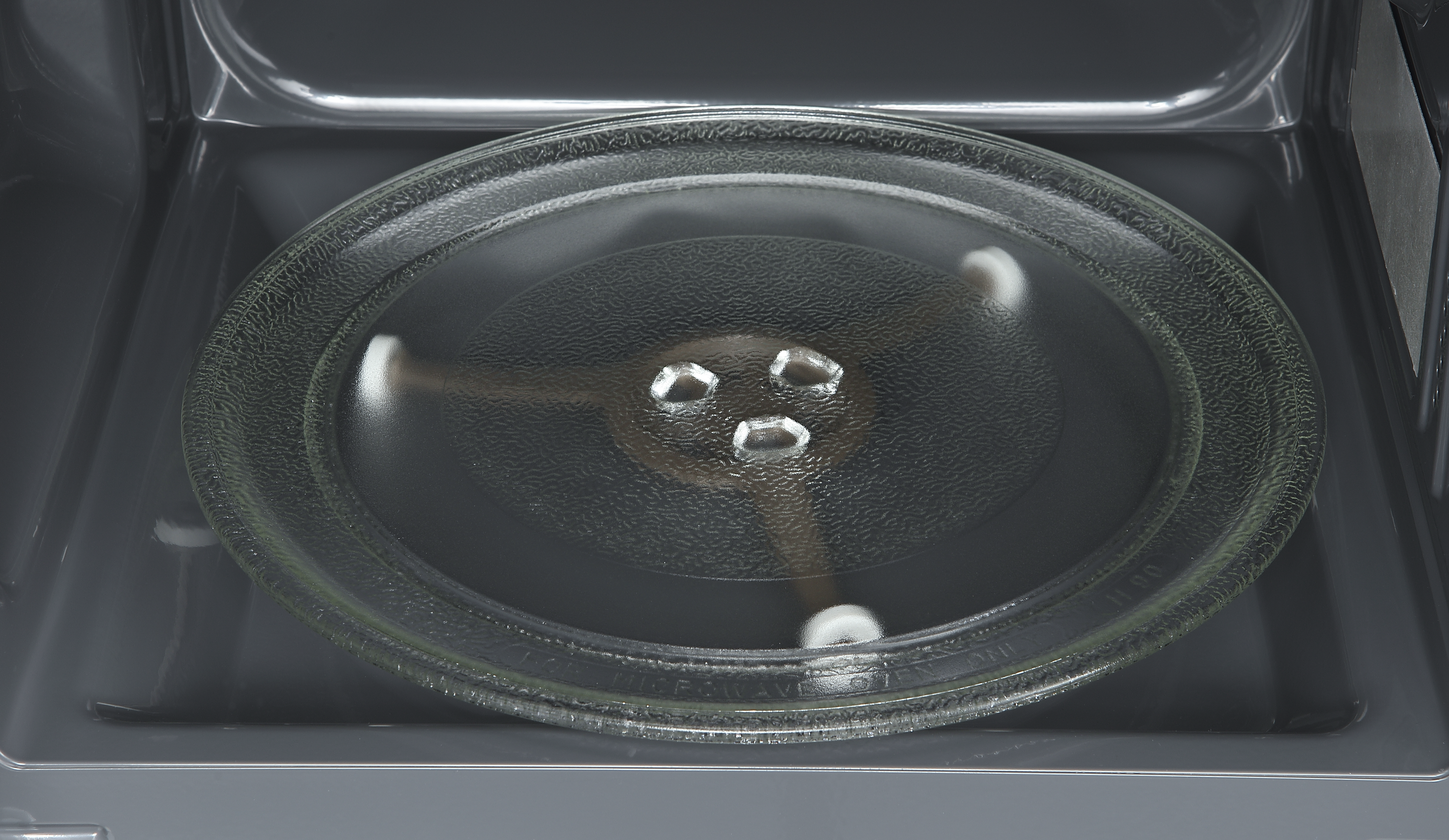 Okrągły szklany talerz obrotowy z trzema punktami podparcia w kuchence mikrofalowej.