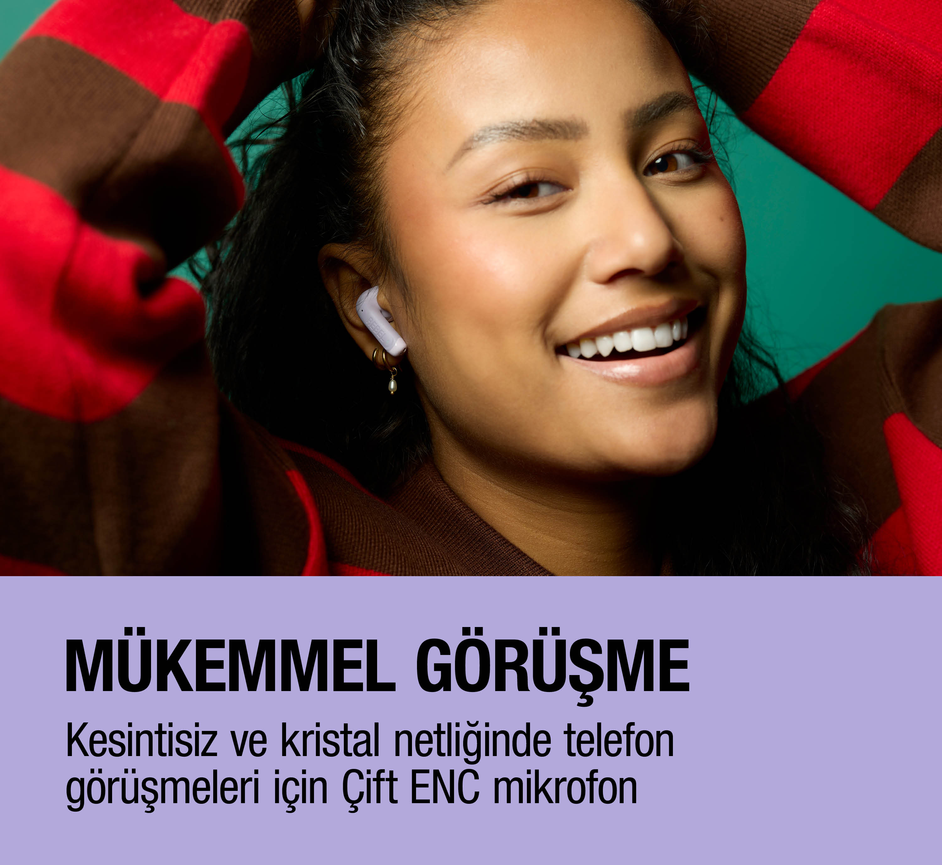 Kulak içi kulaklıkla ve çizgili kazakla gülümseyen kadın.