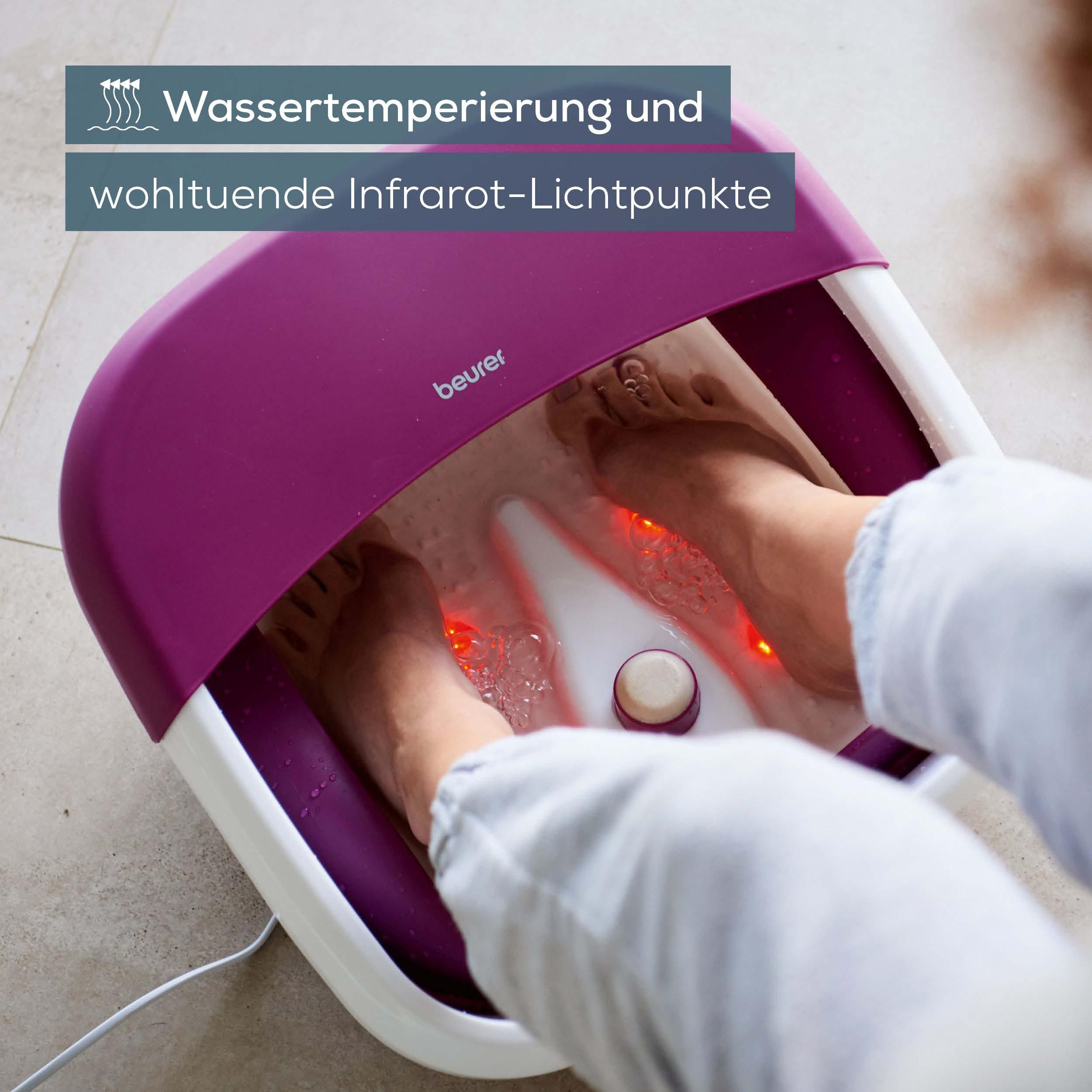 Füße in einem lila und weißen Fußbad mit roten Infrarotlichtern.