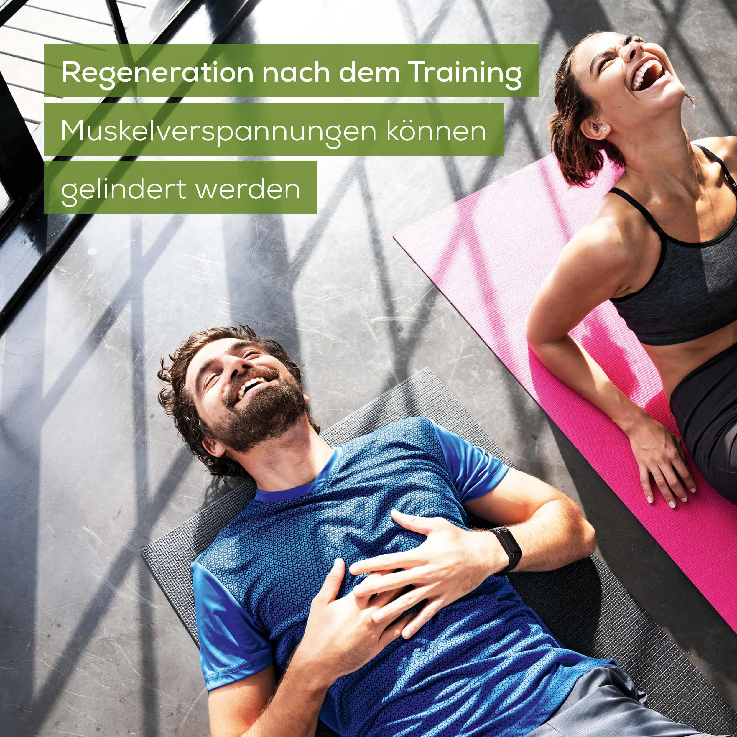 Mann und Frau liegen lachend auf Matten nach dem Training.