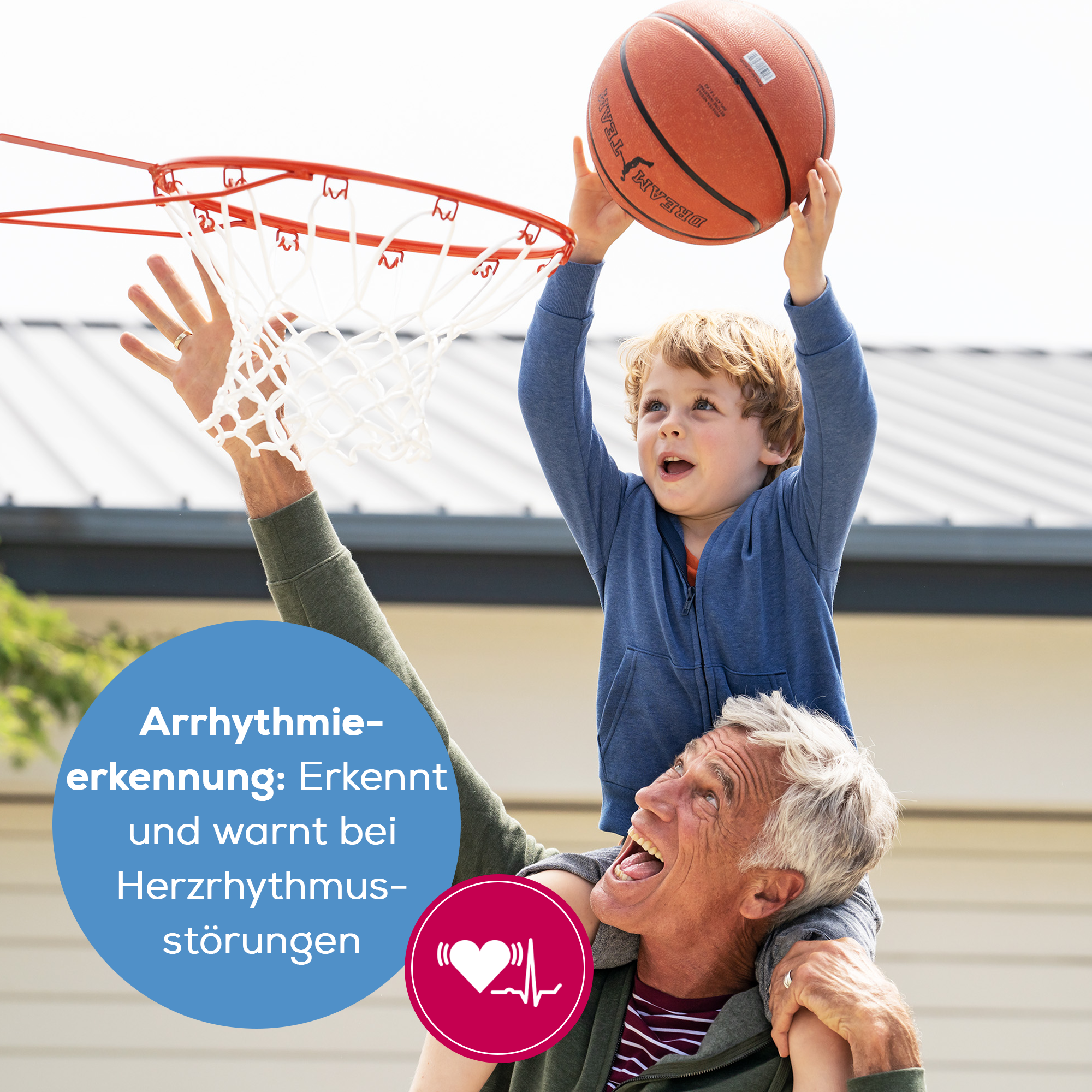 Ein Junge reitet auf den Schultern eines Mannes und hält einen Basketball über einem Basketballkorb.