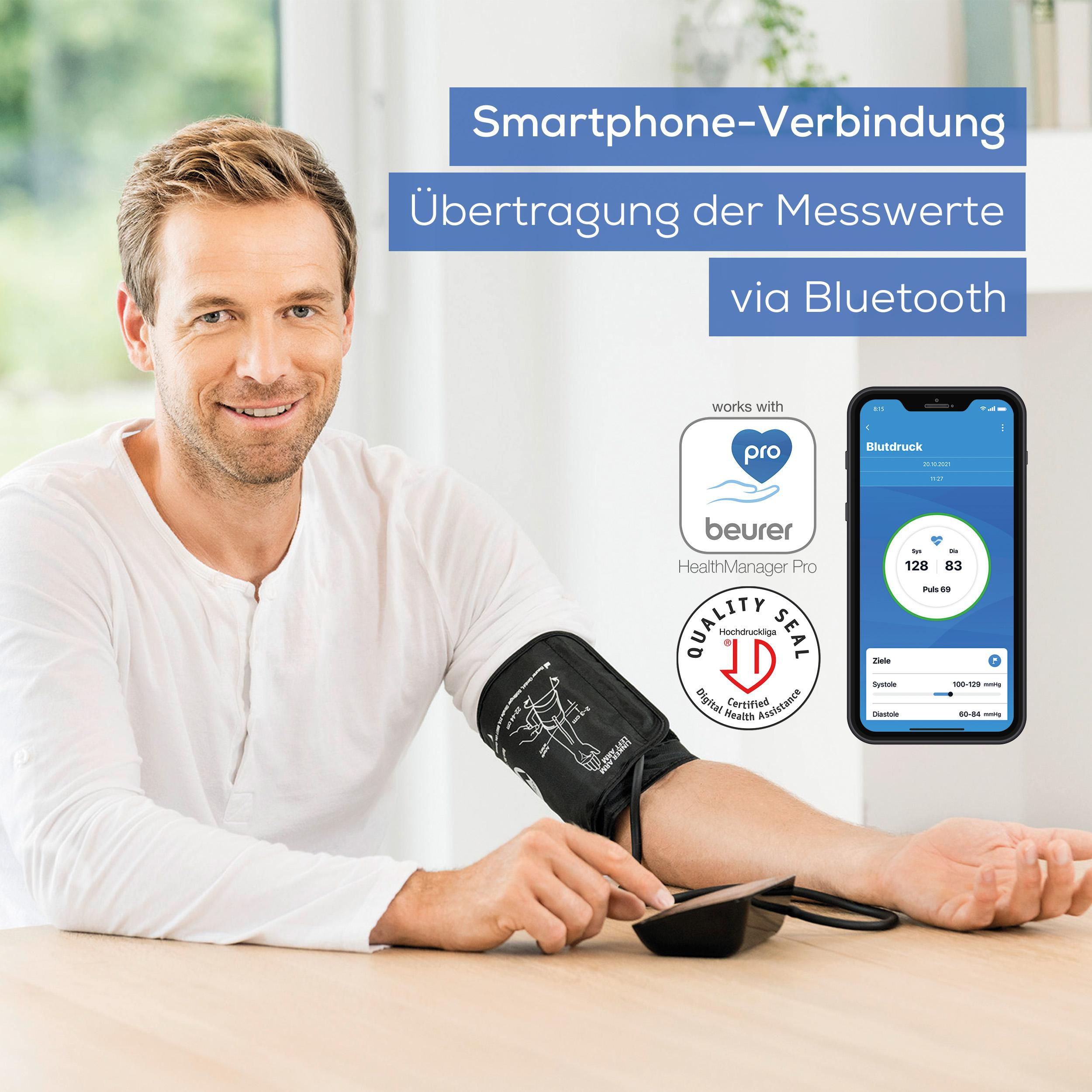 Mann mit Blutdruckmanschette am Arm, Smartphone mit App zeigt Werte an.