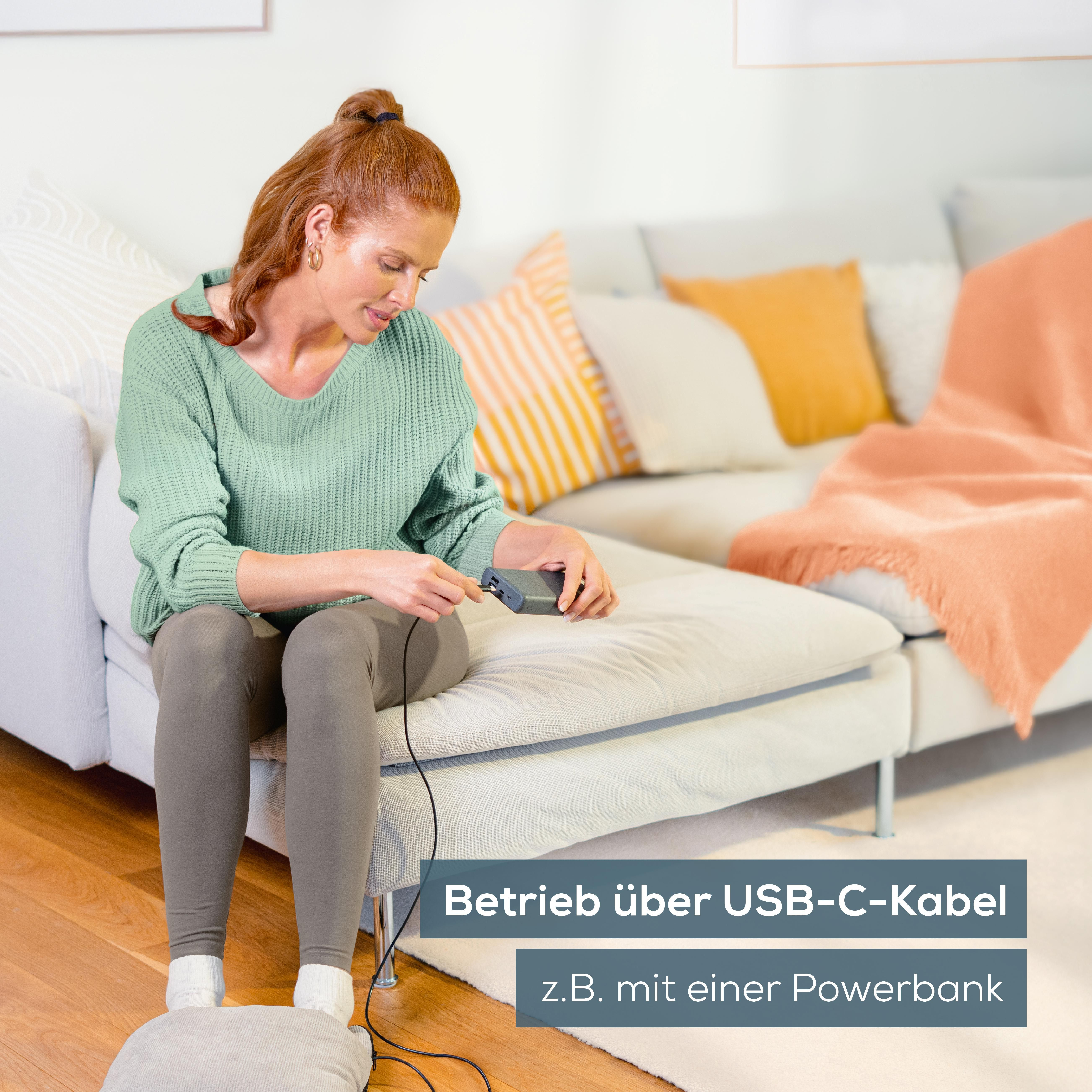 Frau mit roten Haaren steckt ein graues Kabel in ein Powerbank-Gerät.
