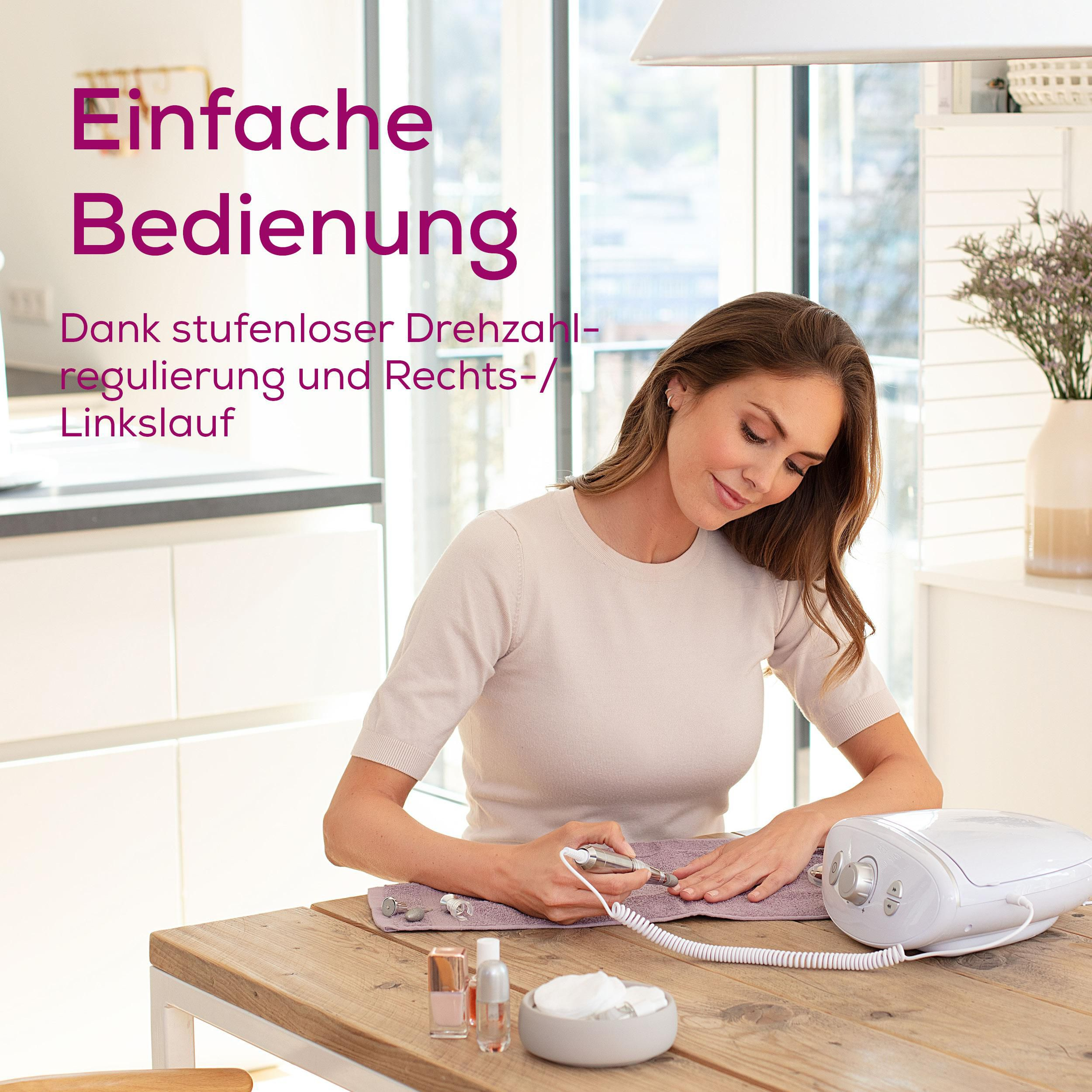 Frau macht Maniküre mit elektrischem Gerät an Holztisch. Produkte liegen daneben.