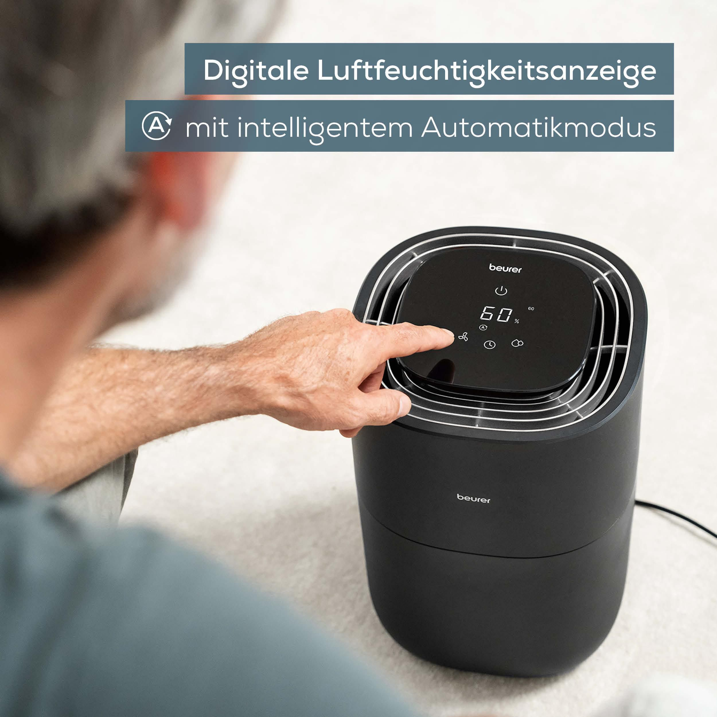 Ein Mann bedient einen schwarzen Luftbefeuchter mit digitaler Anzeige.
