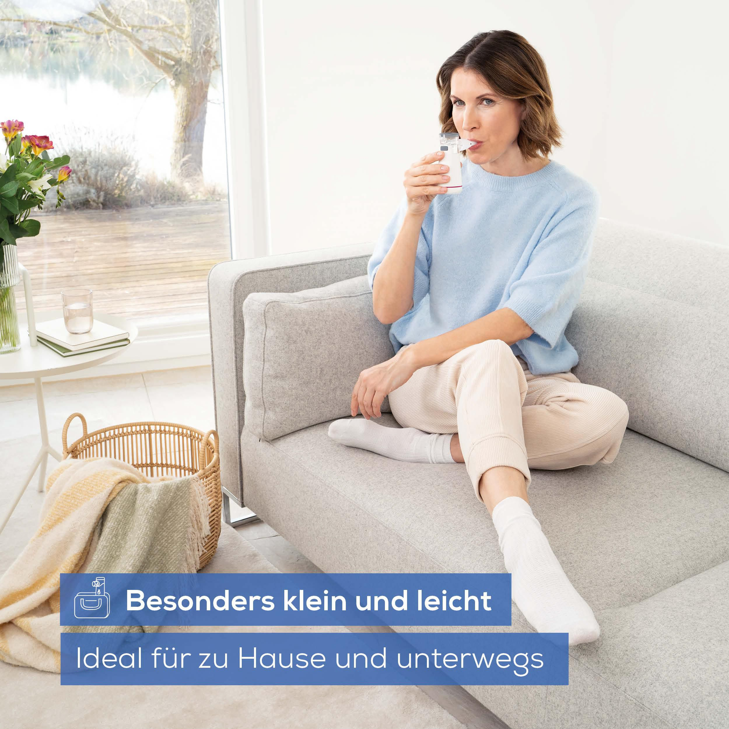 Frau sitzt auf Sofa und nutzt ein Inhalationsgerät. Blaue Texteinblendung.