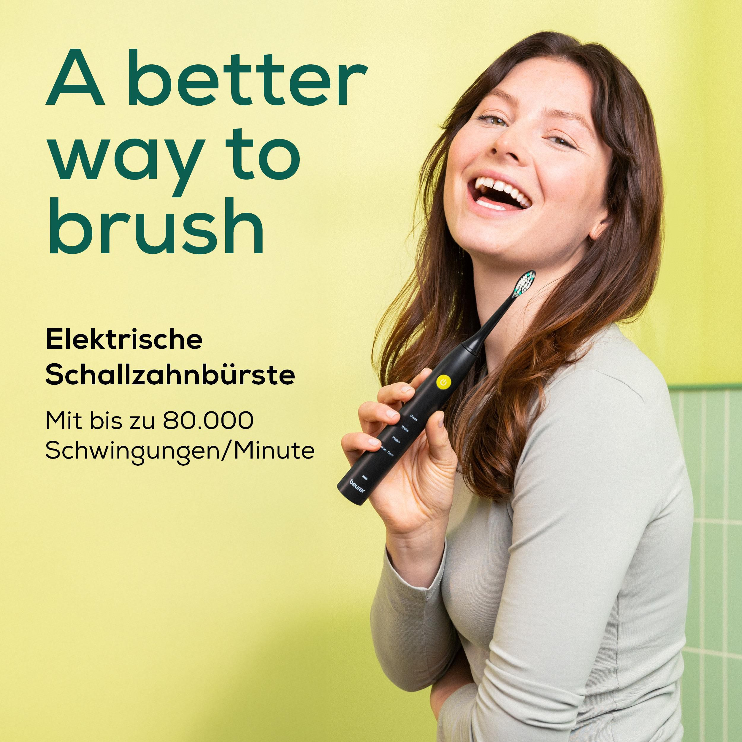 Eine lächelnde Frau hält eine schwarze elektrische Schallzahnbürste vor einem gelb-grünen Hintergrund.