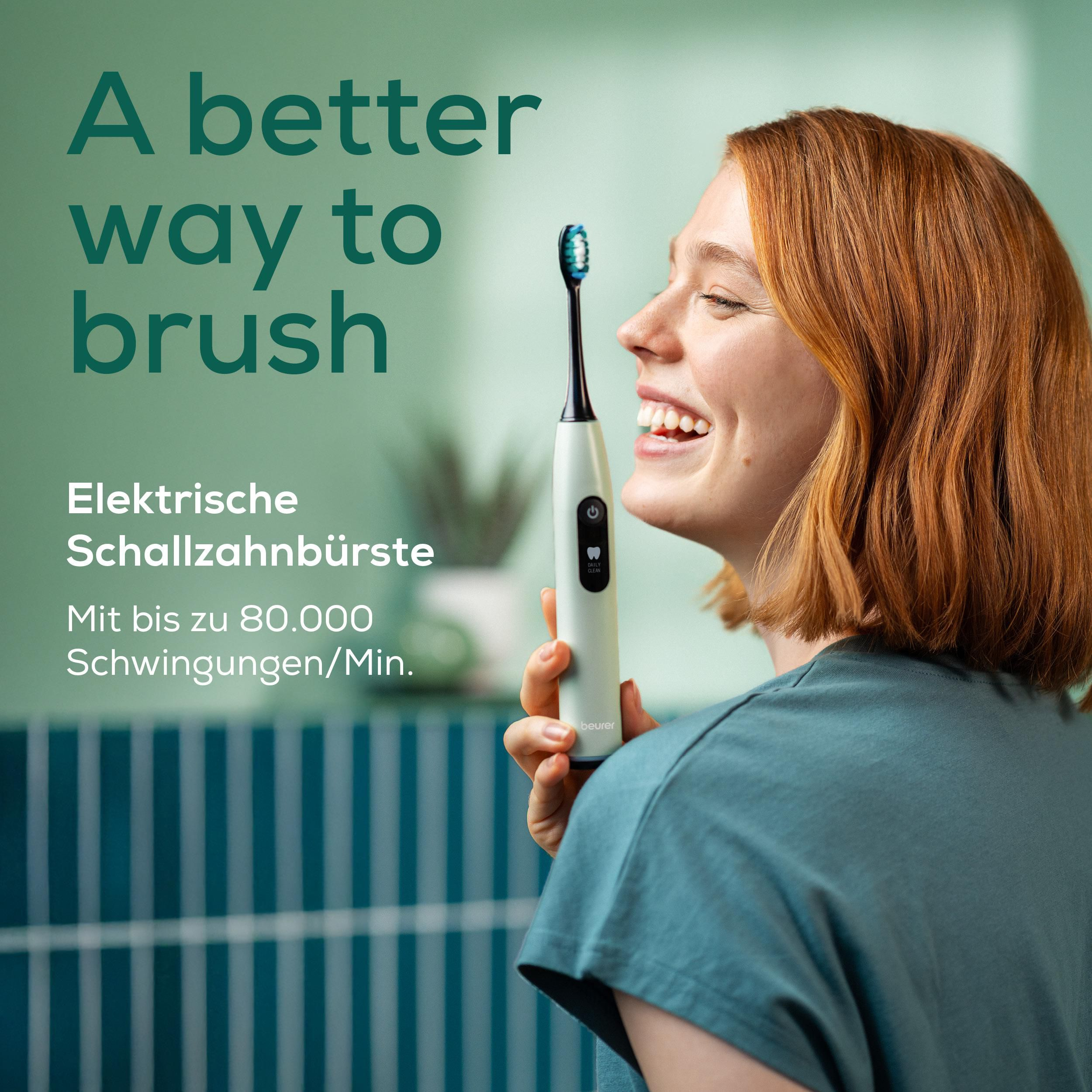 Eine Frau mit roten Haaren hält eine elektrische Zahnbürste. Hintergrund ist grün.