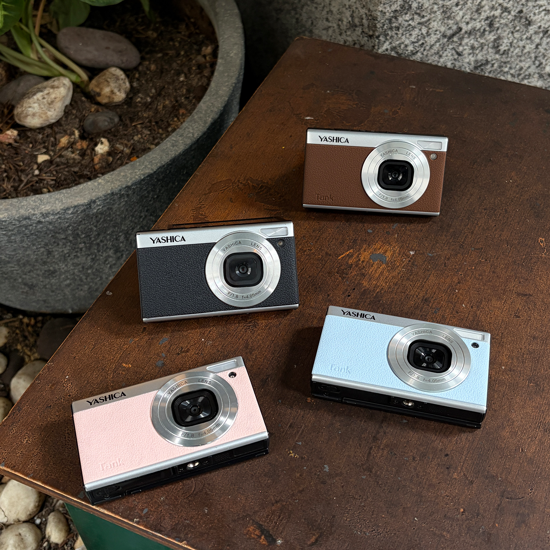 Ahşap yüzey üzerinde pembe, mavi, siyah ve kahverengi dört adet Yashica Tank kamera.