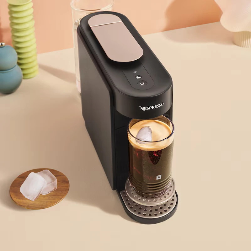 Czarny ekspres Nespresso parzy mrożoną kawę do szklanki z kostkami lodu.