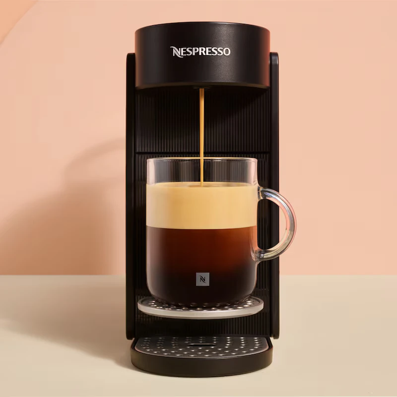 Ekspres Nespresso parzy kawę do przezroczystej filiżanki z dwoma warstwami.