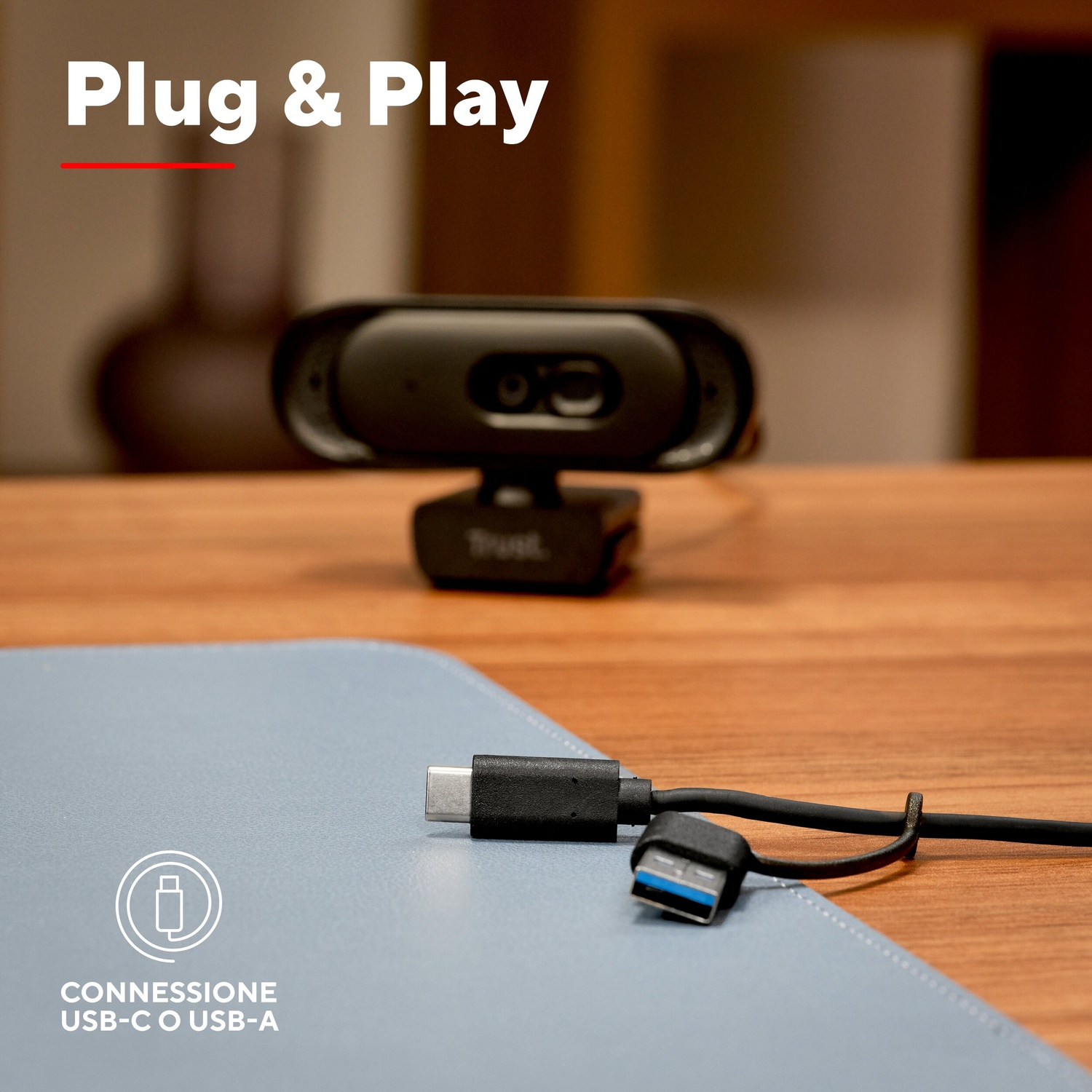 Webcam con connessione USB-C e USB-A su tavolo di legno.