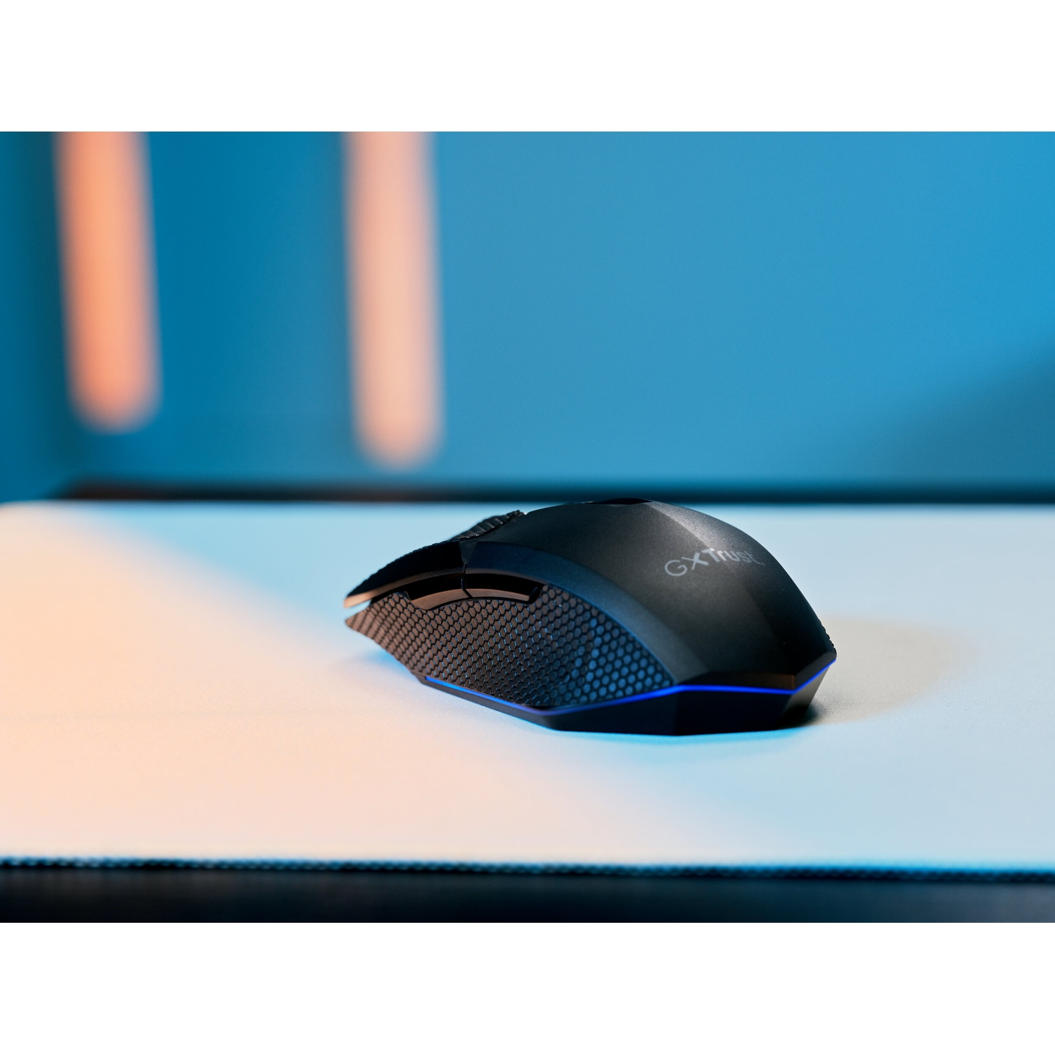 Un mouse gaming nero con illuminazione blu su un tappetino bianco.