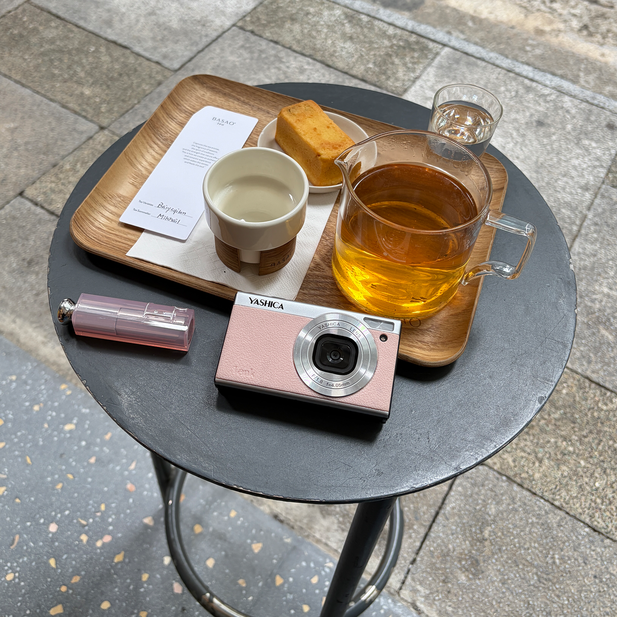 Pembe bir Yashica Tank kamera, ruj ve çay ile kek bulunan ahşap tepsi.