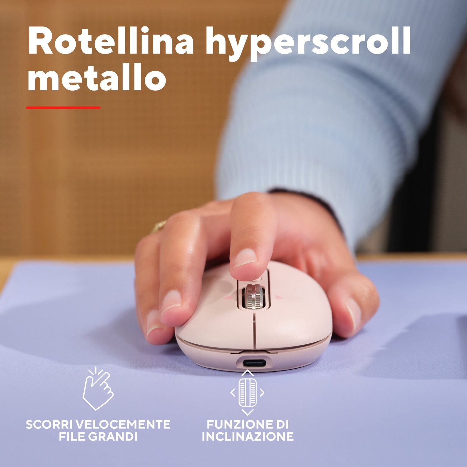 Una mano usa un mouse rosa con rotellina in metallo su un tappetino viola.