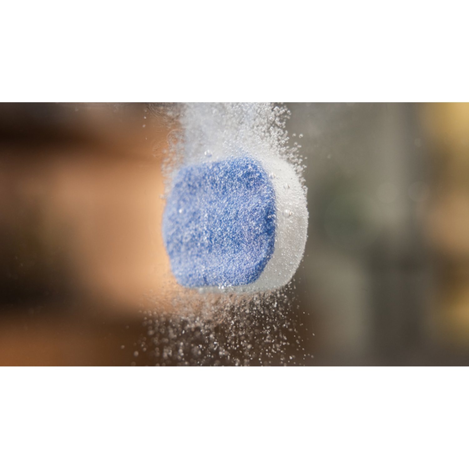 A blue and white cleaning tablet dissolving in water, creating bubbles.