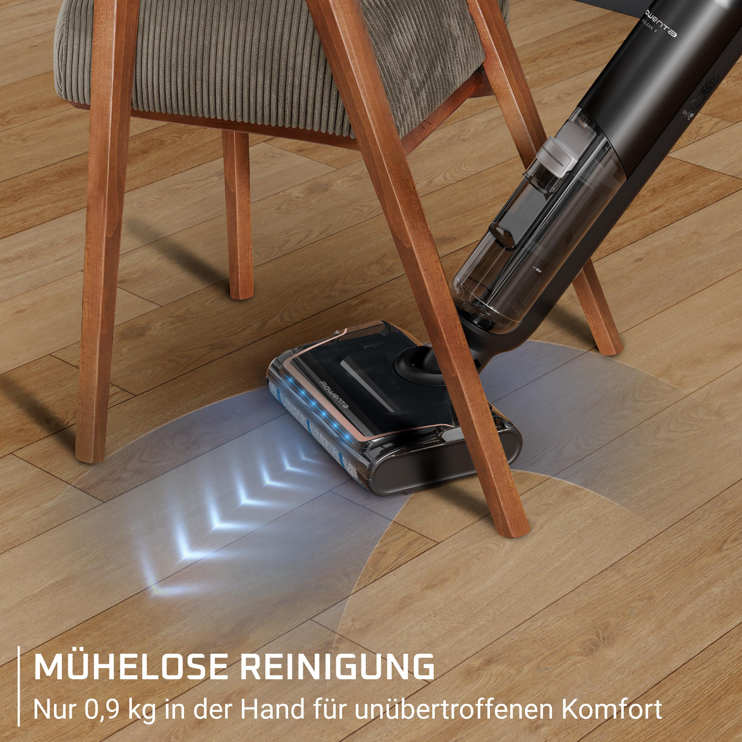 Ein schwarzer Akku-Staubsauger reinigt einen Holzboden neben einem Stuhl.