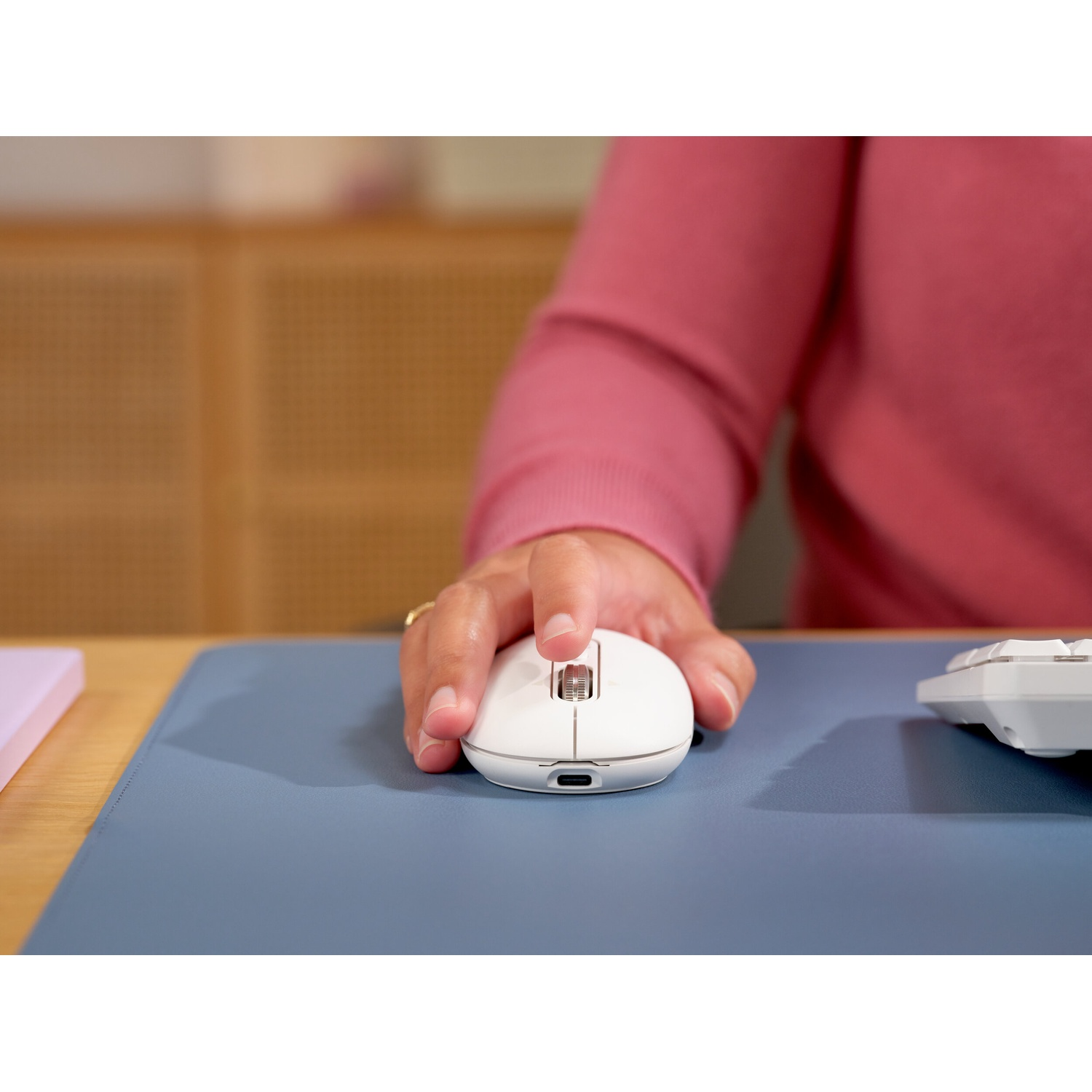 Una mano aziona un mouse bianco su un tappetino blu.