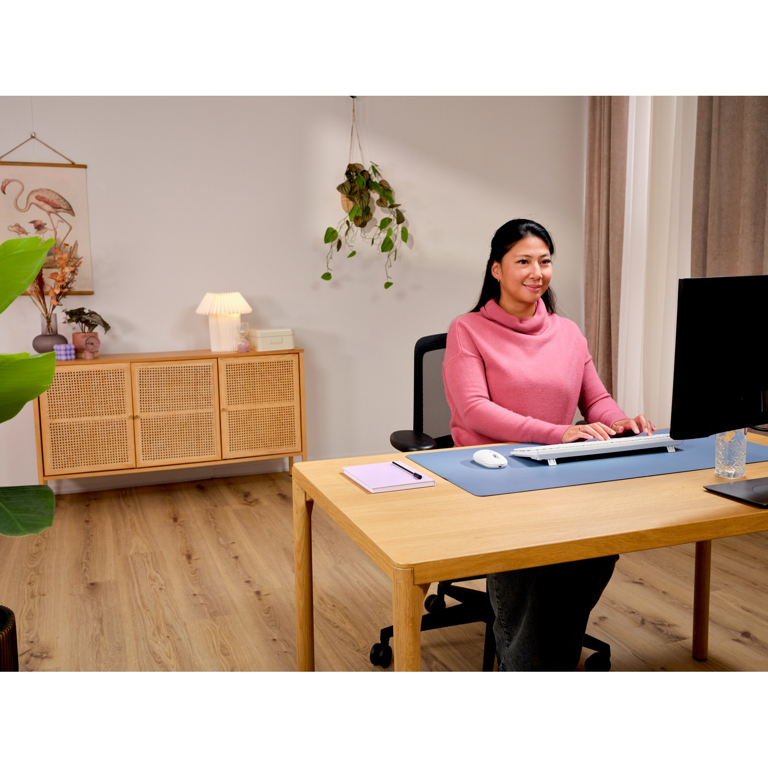 Donna alla scrivania con tastiera e mouse, credenza sullo sfondo.
