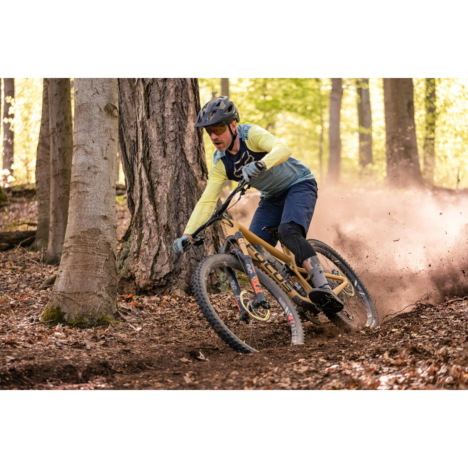 Un mountain biker pedala su un sentiero nel bosco sollevando polvere.