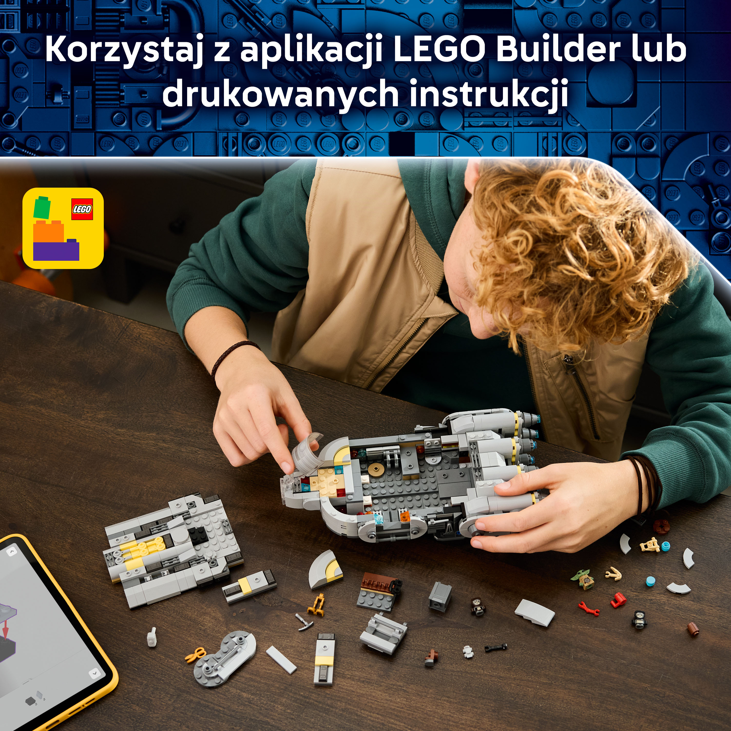 Chłopiec buduje szary statek kosmiczny z klocków LEGO, obok leżą części i tablet.