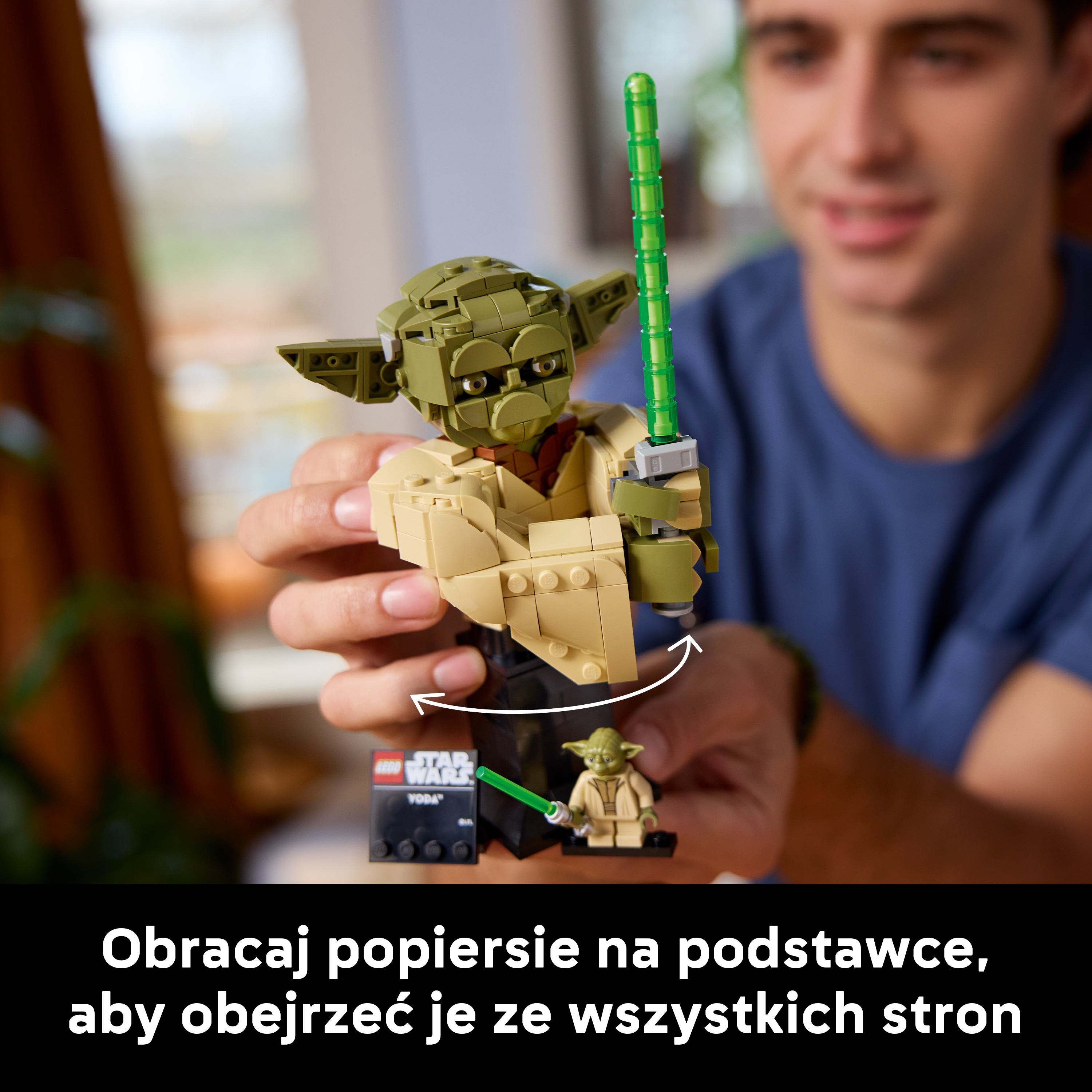 Mężczyzna trzyma figurkę Lego Yody z zielonym mieczem świetlnym.