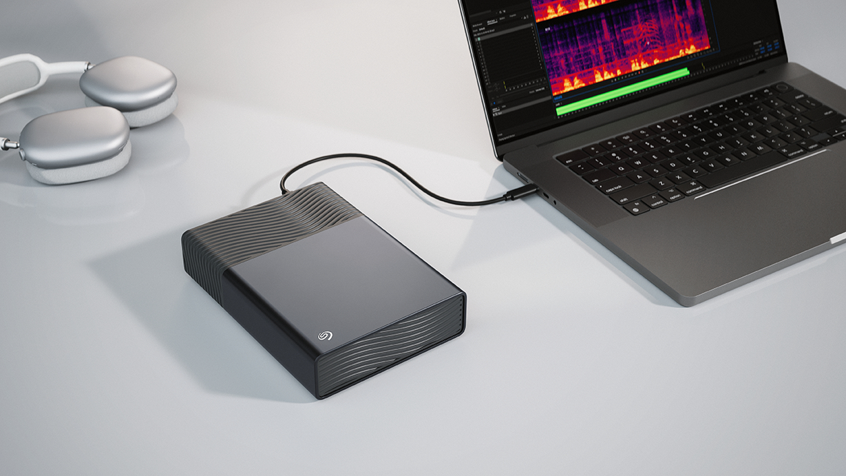 Externe Festplatte an einen Laptop angeschlossen, Kopfhörer daneben.