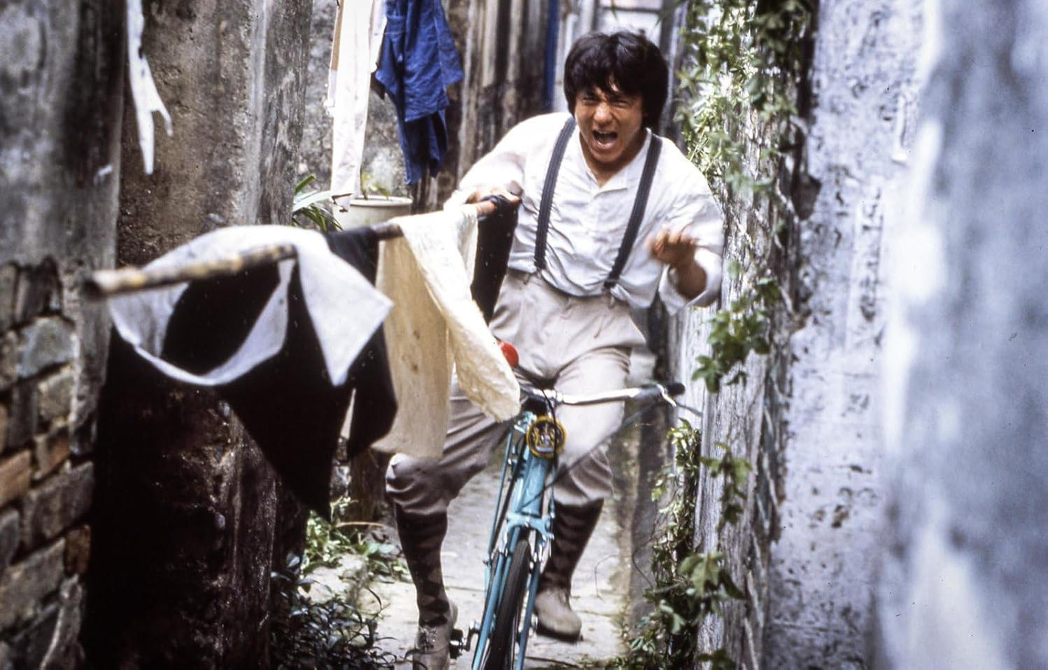Mann auf Fahrrad in enger Gasse mit Wäscheleine.