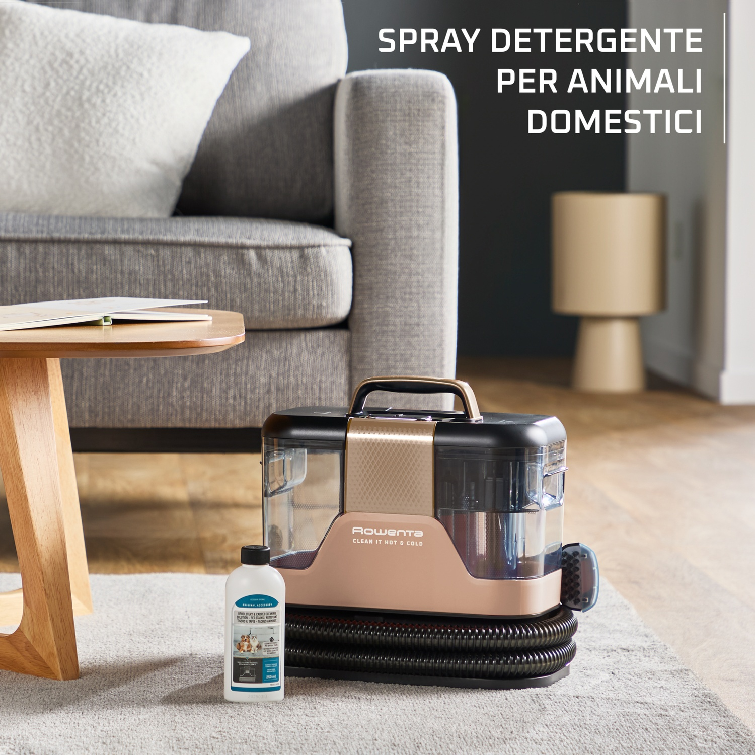 Un pulitore per tappeti oro rosa e nero si trova su un tappeto grigio accanto a una bottiglia di soluzione detergente.
