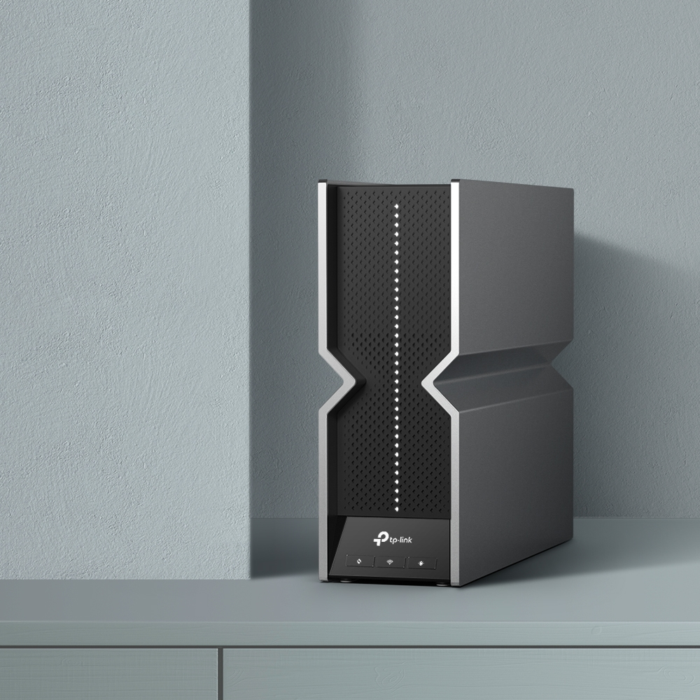 Un router TP-Link gris con panel frontal negro perforado se sienta en un estante.