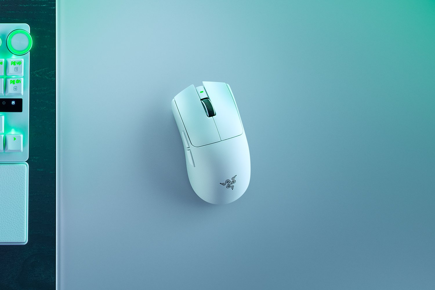Un mouse da gaming bianco riposa su un tappetino blu accanto a una tastiera.