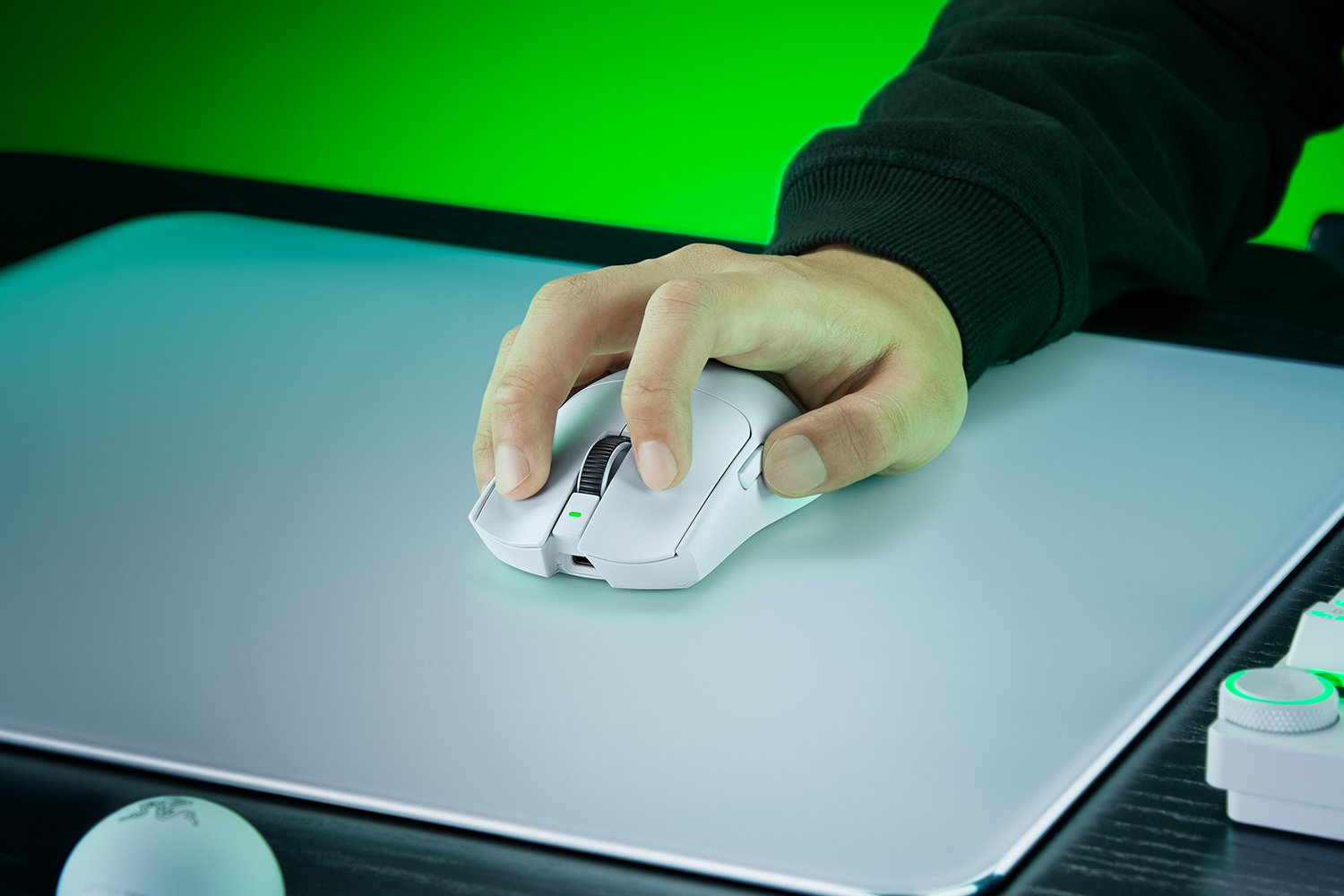 Una mano usa un mouse bianco su un tappetino grigio con sfondo verde.