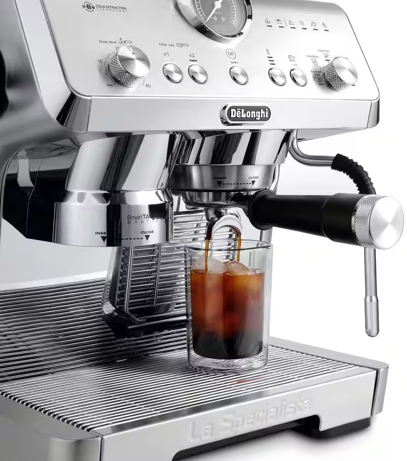 Une machine à expresso DeLonghi prépare du café dans un verre avec des glaçons.