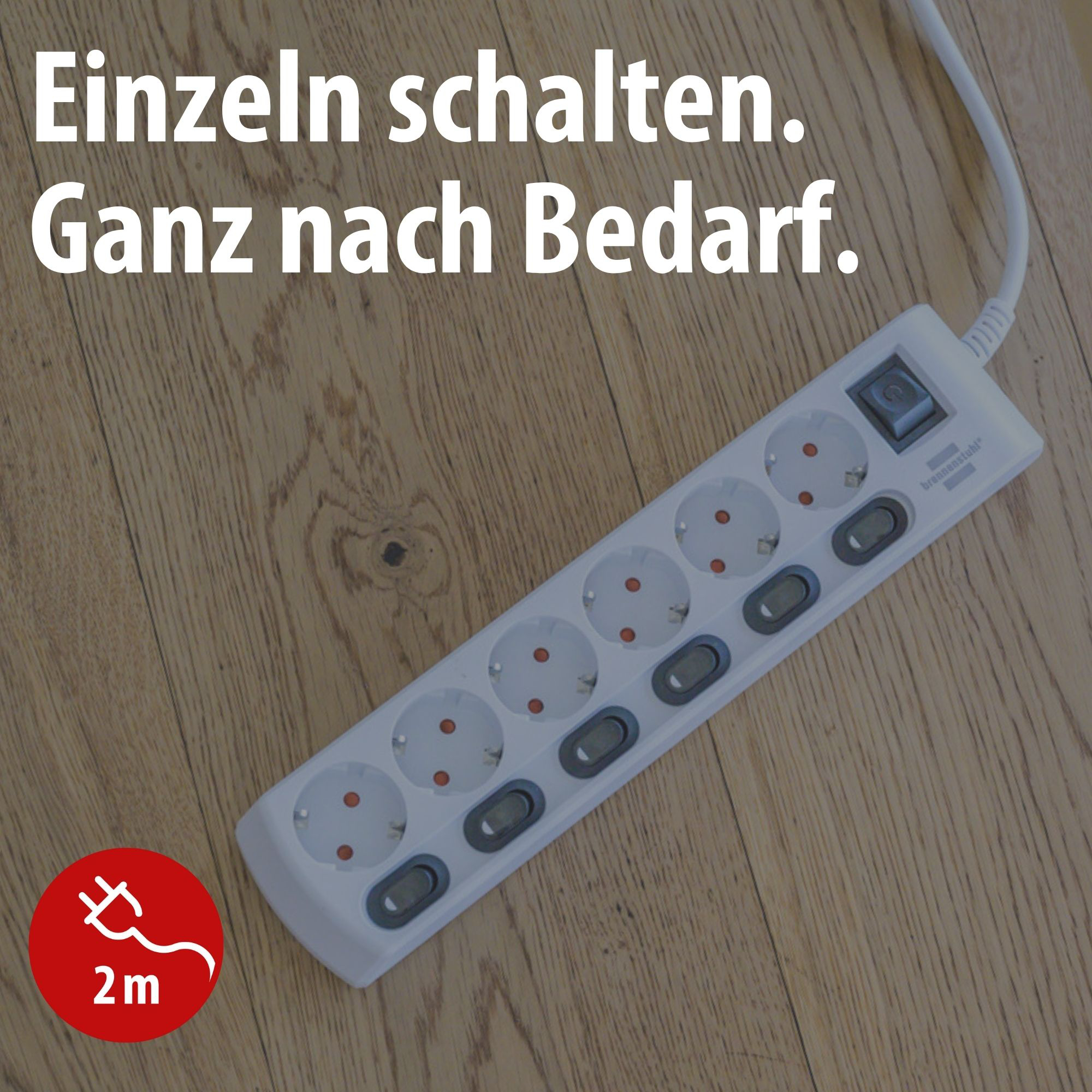 Eine weiße Steckdosenleiste mit einzelnen Schaltern und Steckplätzen auf Holzboden.