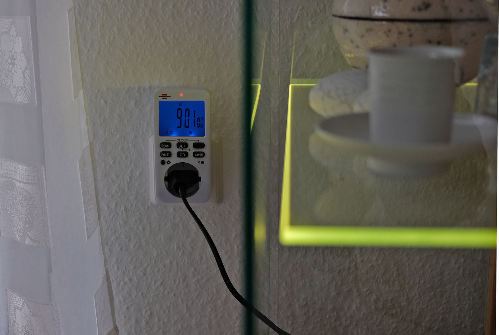 Ein weißer Energiezähler, in die Wand gesteckt, zeigt 901,00 an. Ein schwarzes Kabel verlässt den Zähler.