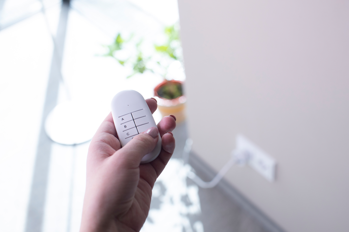 Eine Hand hält eine weiße Fernbedienung mit den Tasten A, B, C.