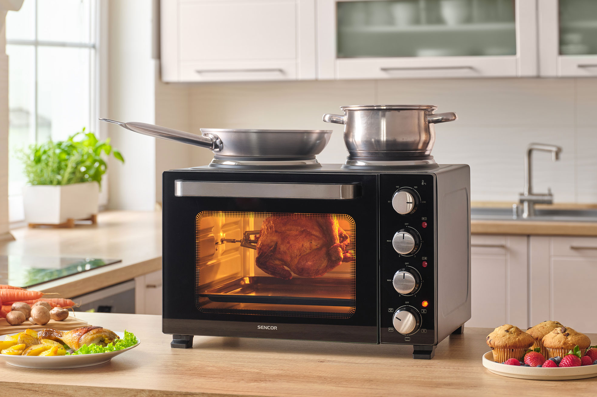 Rotisserie csirke sül fekete sütőben. Edény és fazék van rajta. Étel az oldalon.