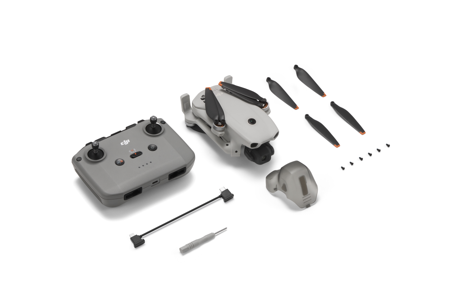 Dron blanco, control remoto gris, hélices de repuesto, tornillos y accesorios sobre fondo blanco.
