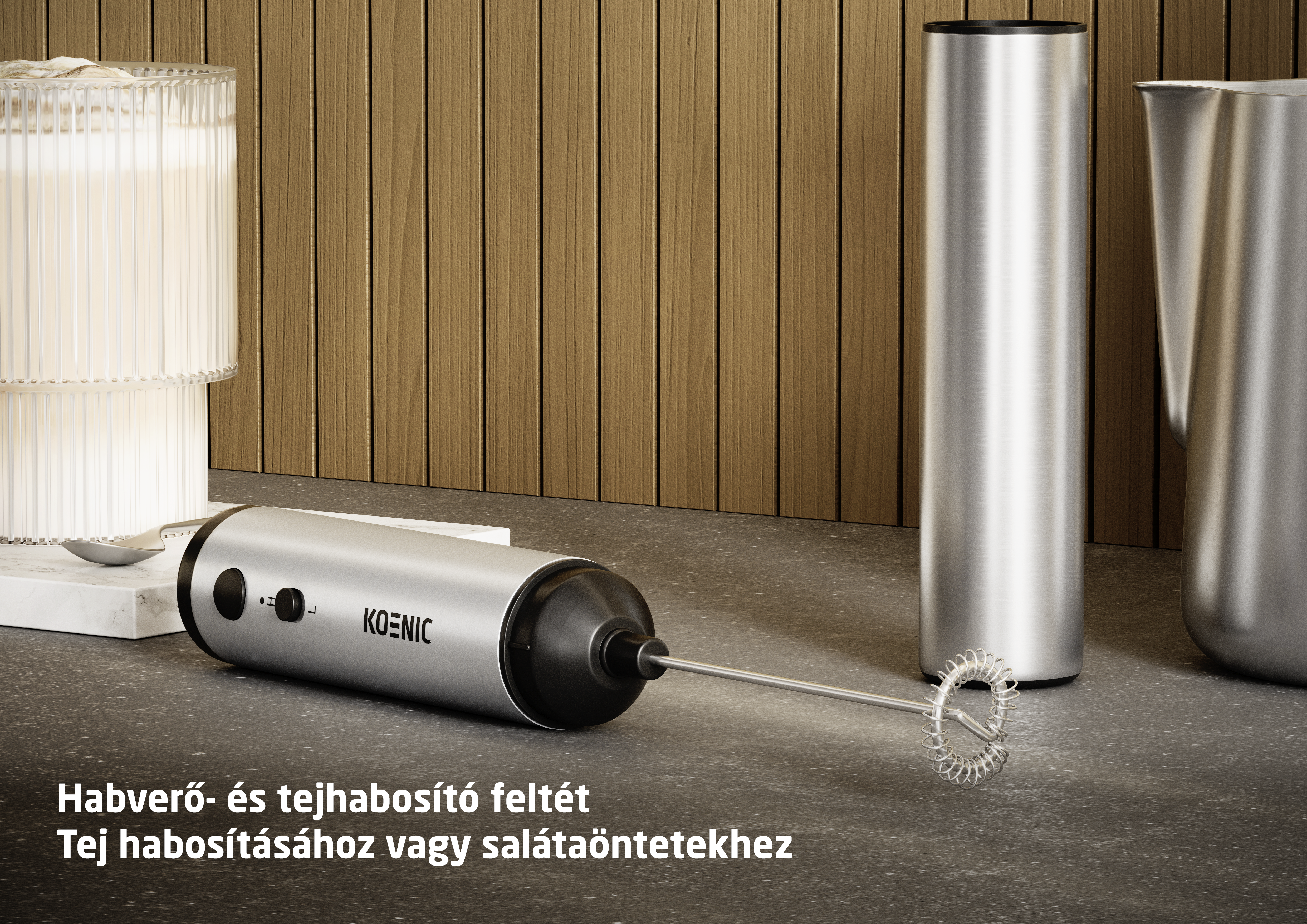 Ezüst tejhabosító habverő feltéttel márványkövön, pohár mellett.