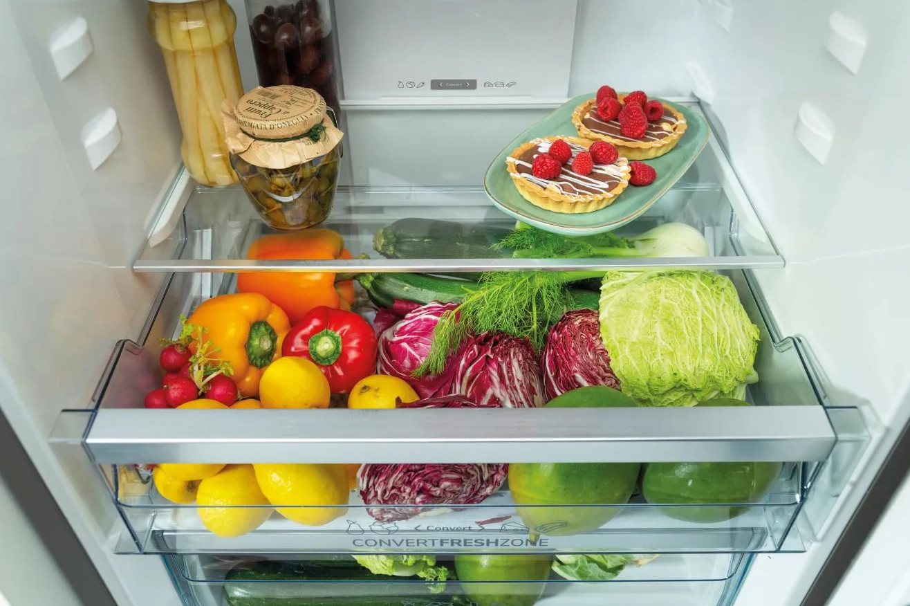 Lodówka wypełniona owocami, warzywami i dwoma małymi tartaletkami.