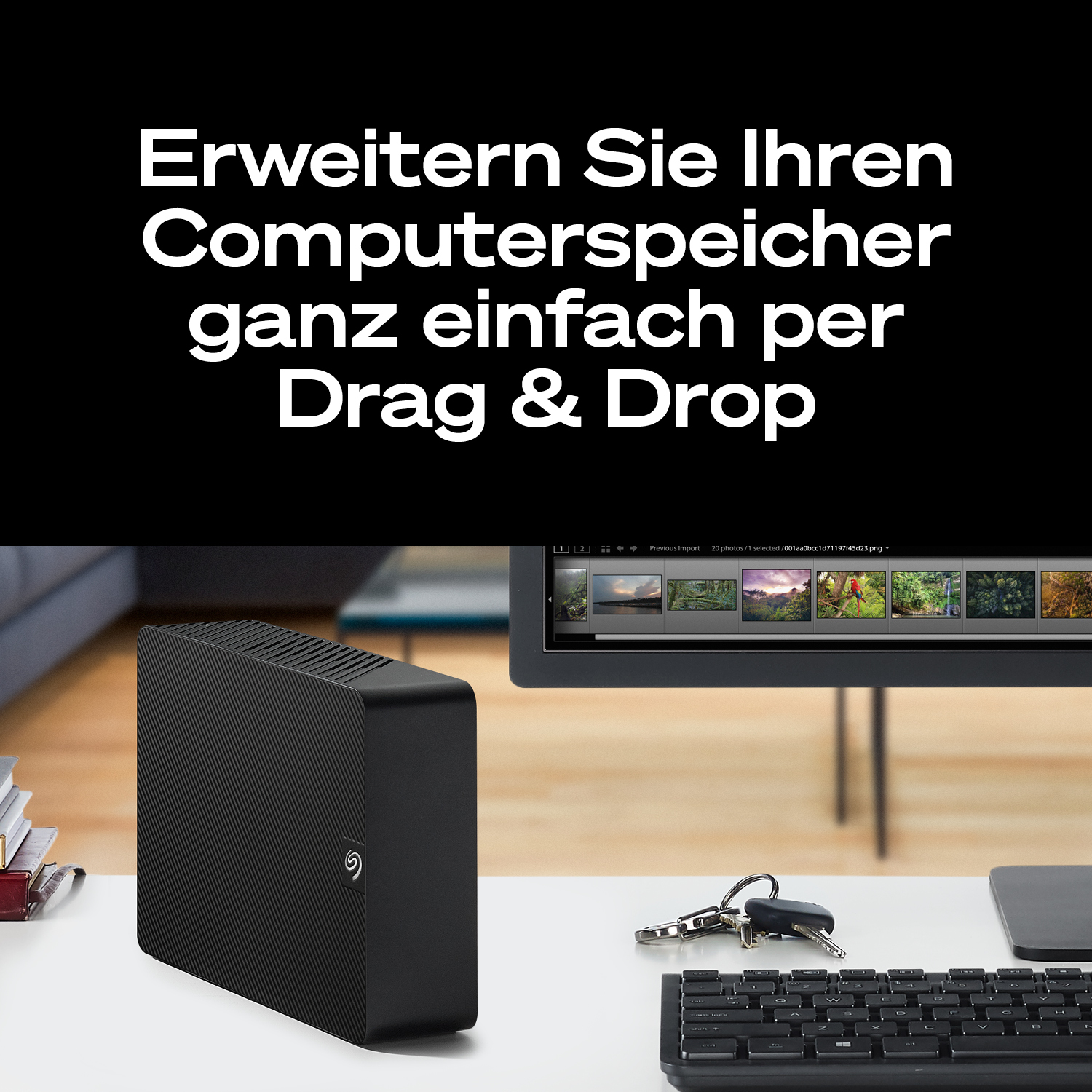 Schwarze externe Festplatte neben Tastatur und Schlüsseln.