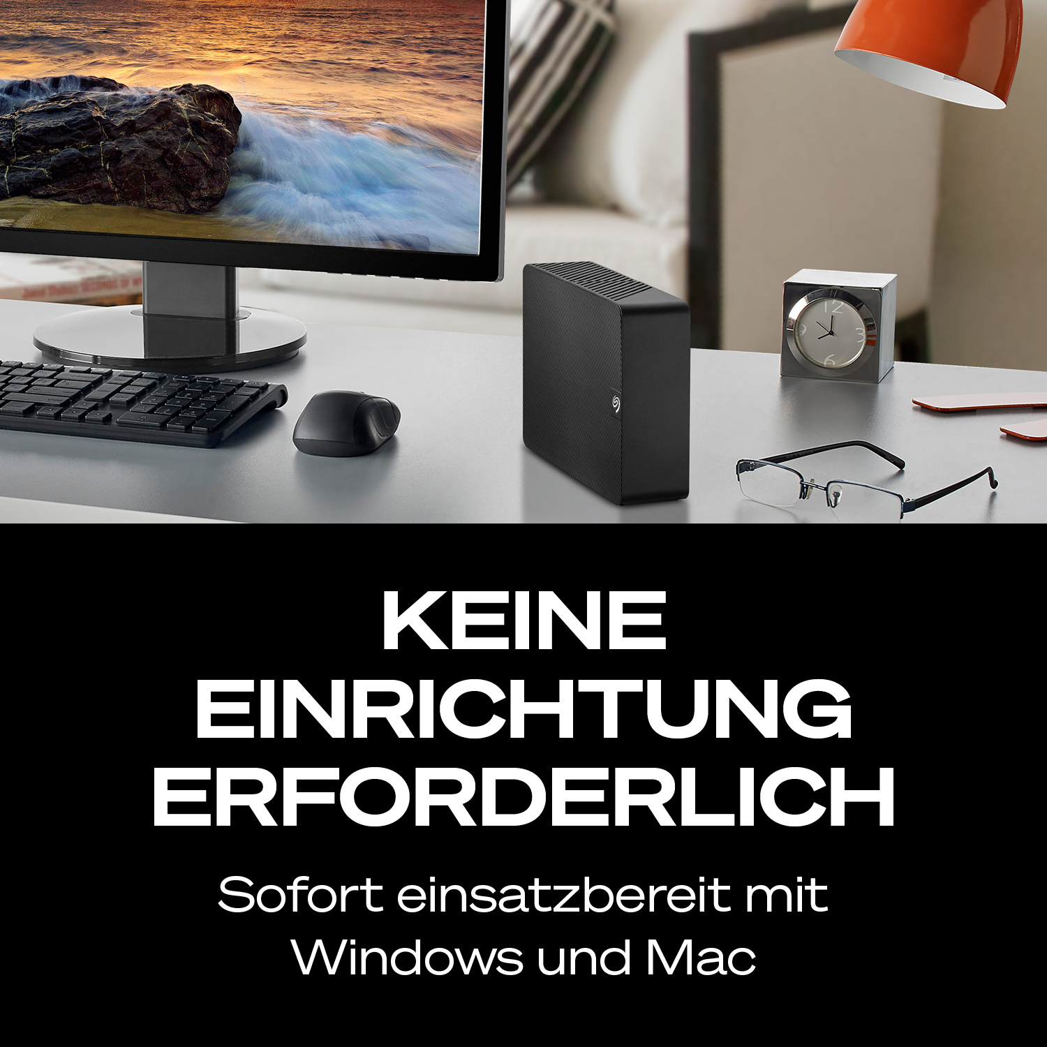 Schreibtisch mit externer Festplatte, Tastatur, Maus, Brille und Uhr.