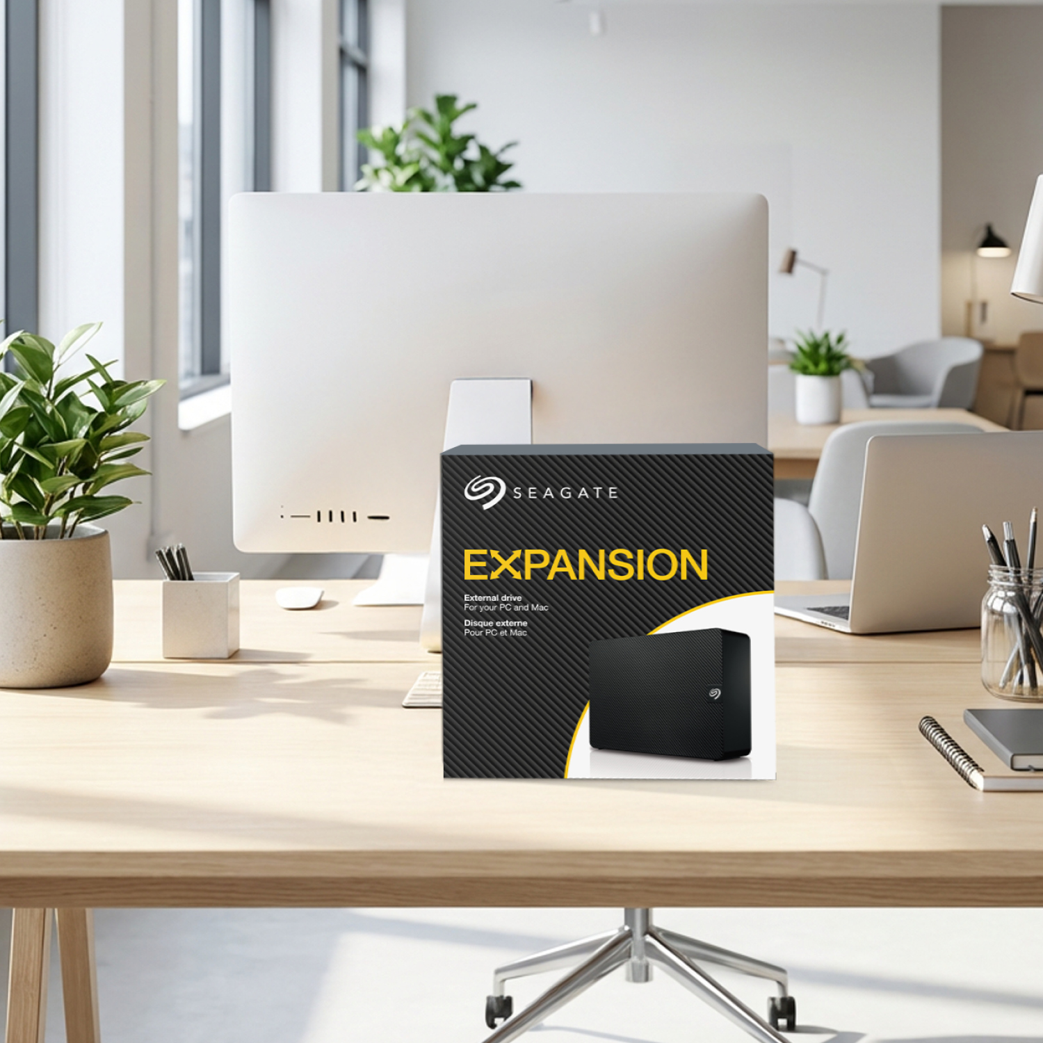 Seagate Expansion Festplatte auf einem Schreibtisch mit Computer und Pflanzen.