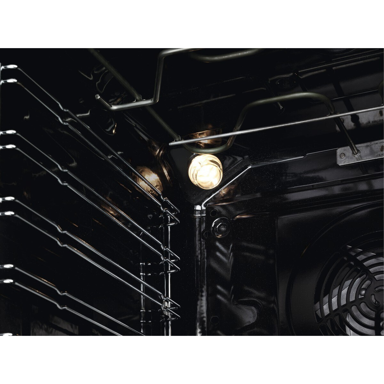 Interno di un forno scuro con griglie metalliche e elemento riscaldante acceso.