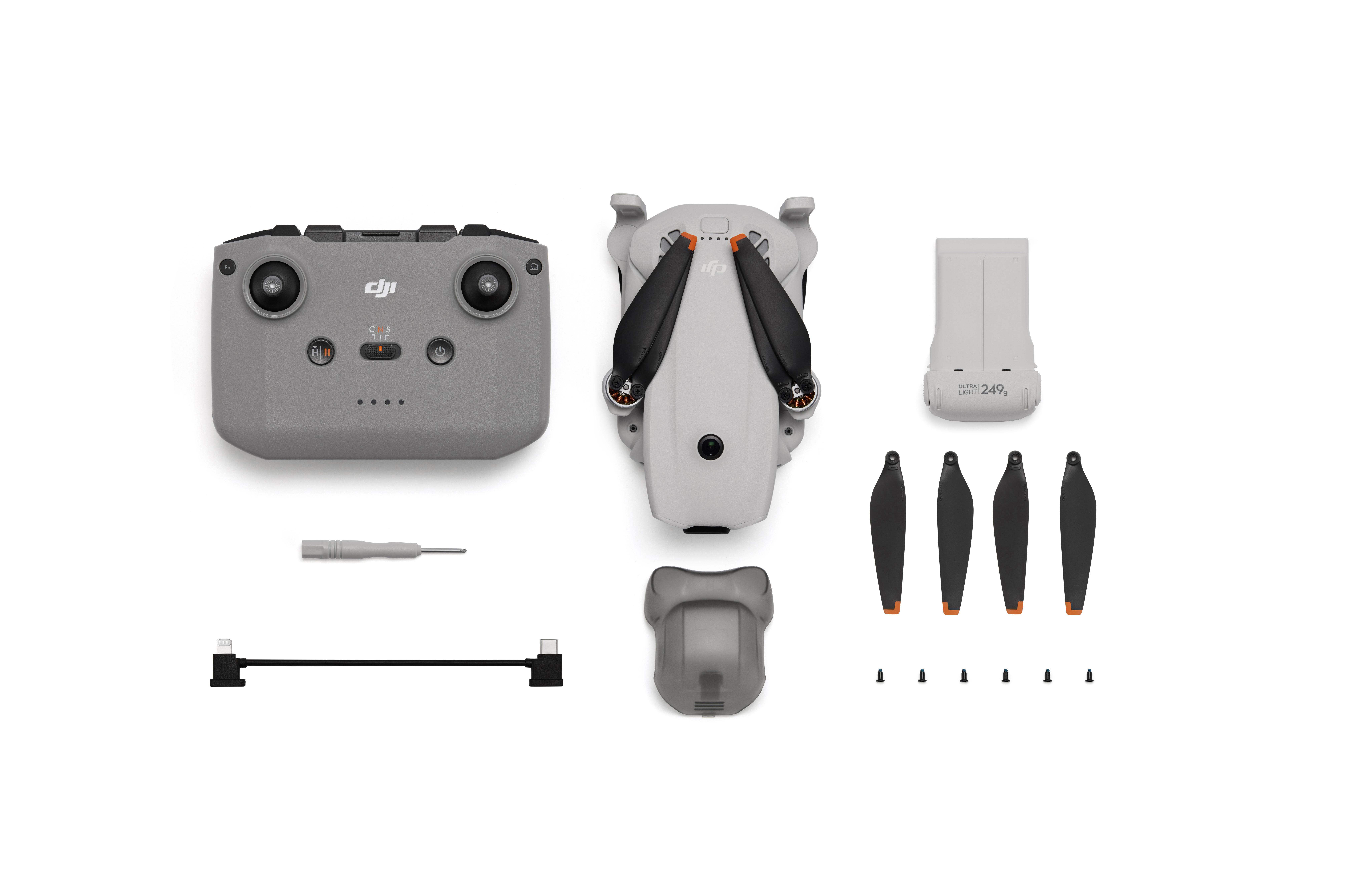 Grauer DJI Controller, Drohne, Akku, Propeller, Schraubendreher und Kabel auf weißem Hintergrund.