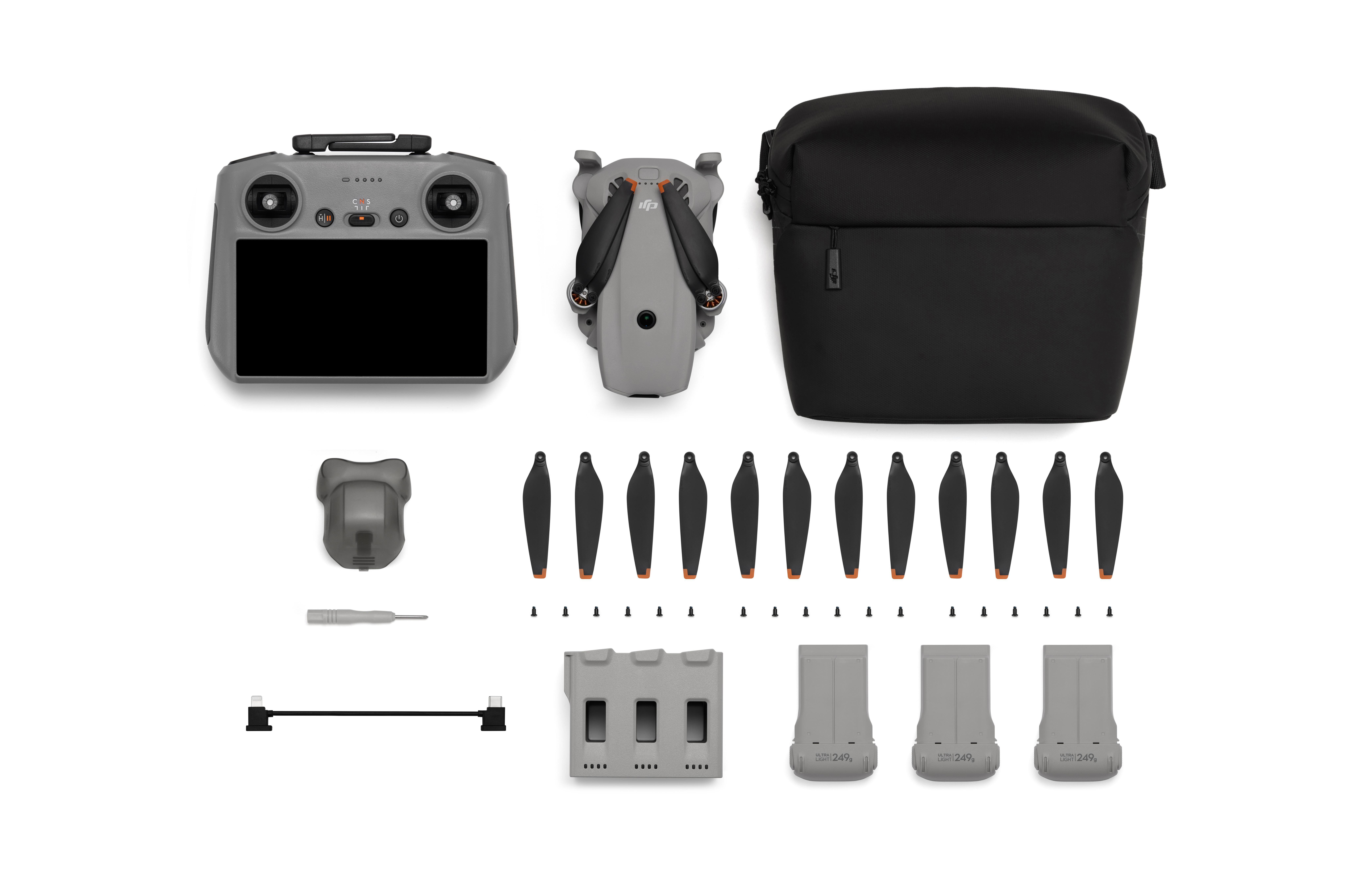 Grauer DJI-Controller, Drohne, schwarze Tasche, Ersatzpropeller, Schraubendreher und Akkus.