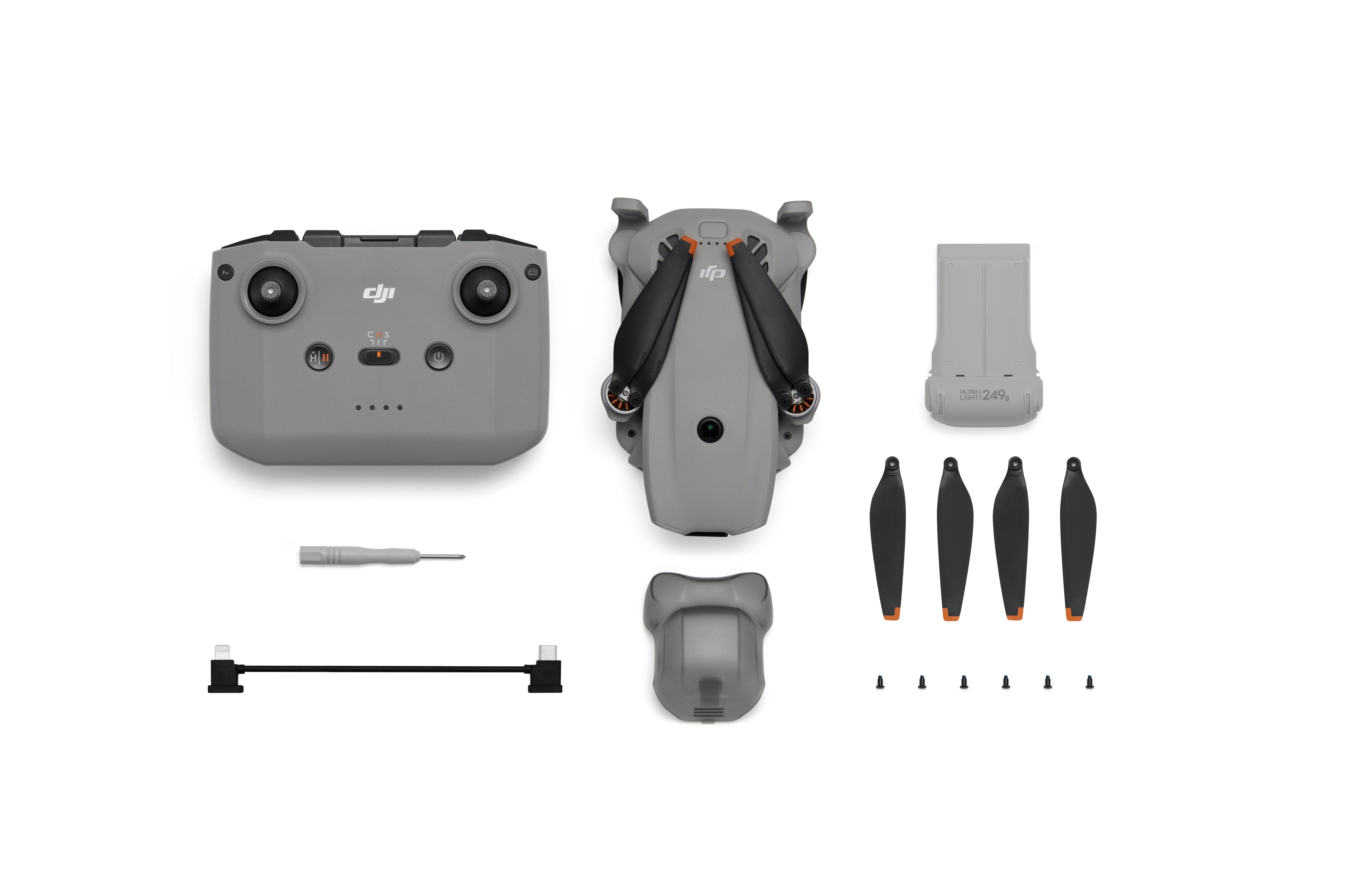Grauer Controller, Drohne, Akku, Propeller, Schraubendreher und Kabel auf weißem Grund.